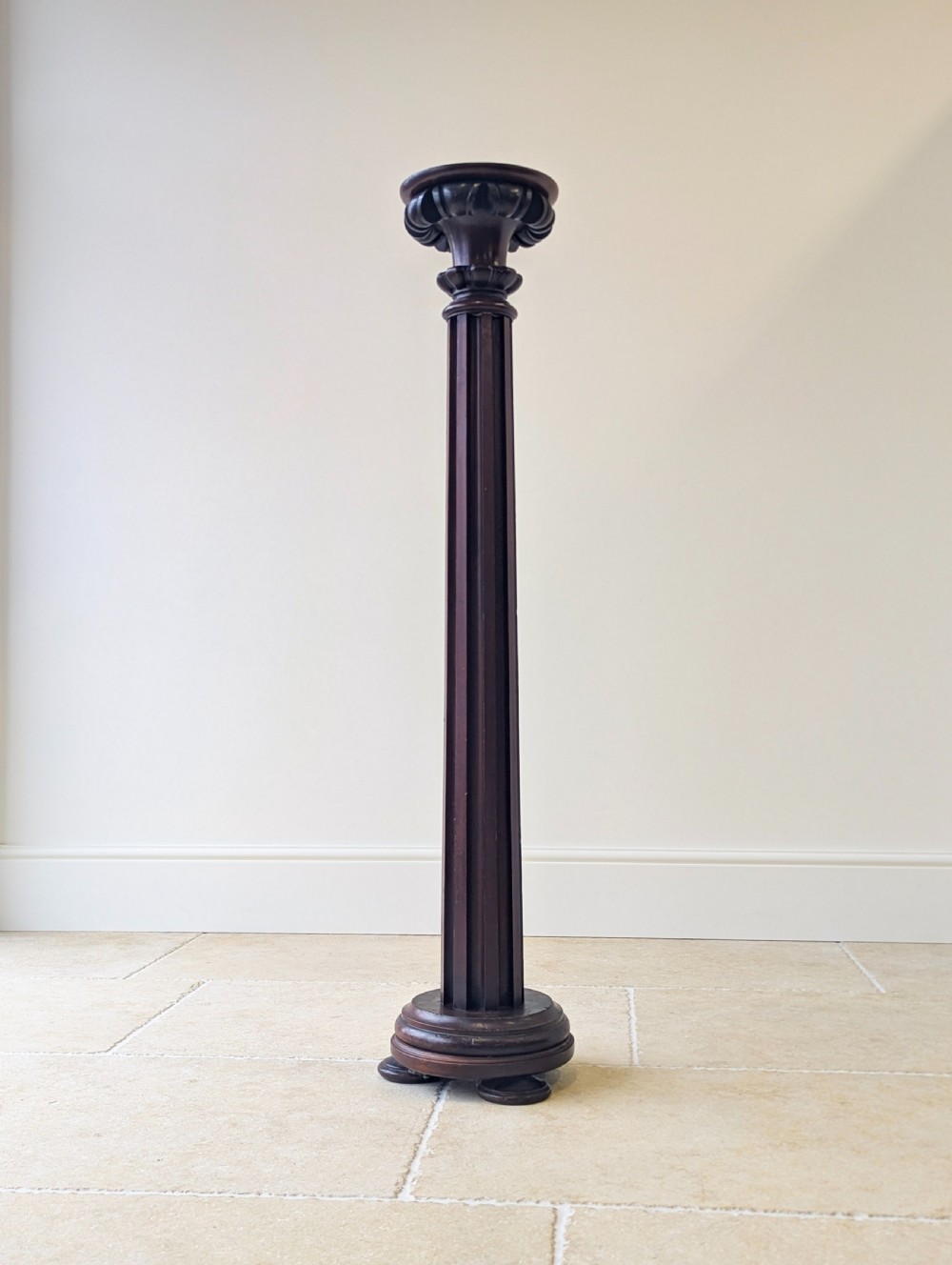 A tall Victorian dark mahogany torchere stand featuring a carved fluted column shaft, gadrooned top rim, and a circular moulded base. View VII