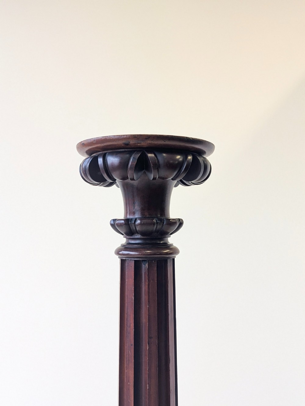 A tall Victorian dark mahogany torchere stand featuring a carved fluted column shaft, gadrooned top rim, and a circular moulded base. View VIII
