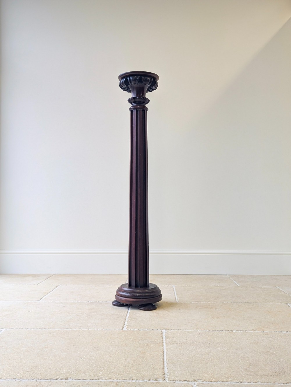 A tall Victorian dark mahogany torchere stand featuring a carved fluted column shaft, gadrooned top rim, and a circular moulded base. View IX