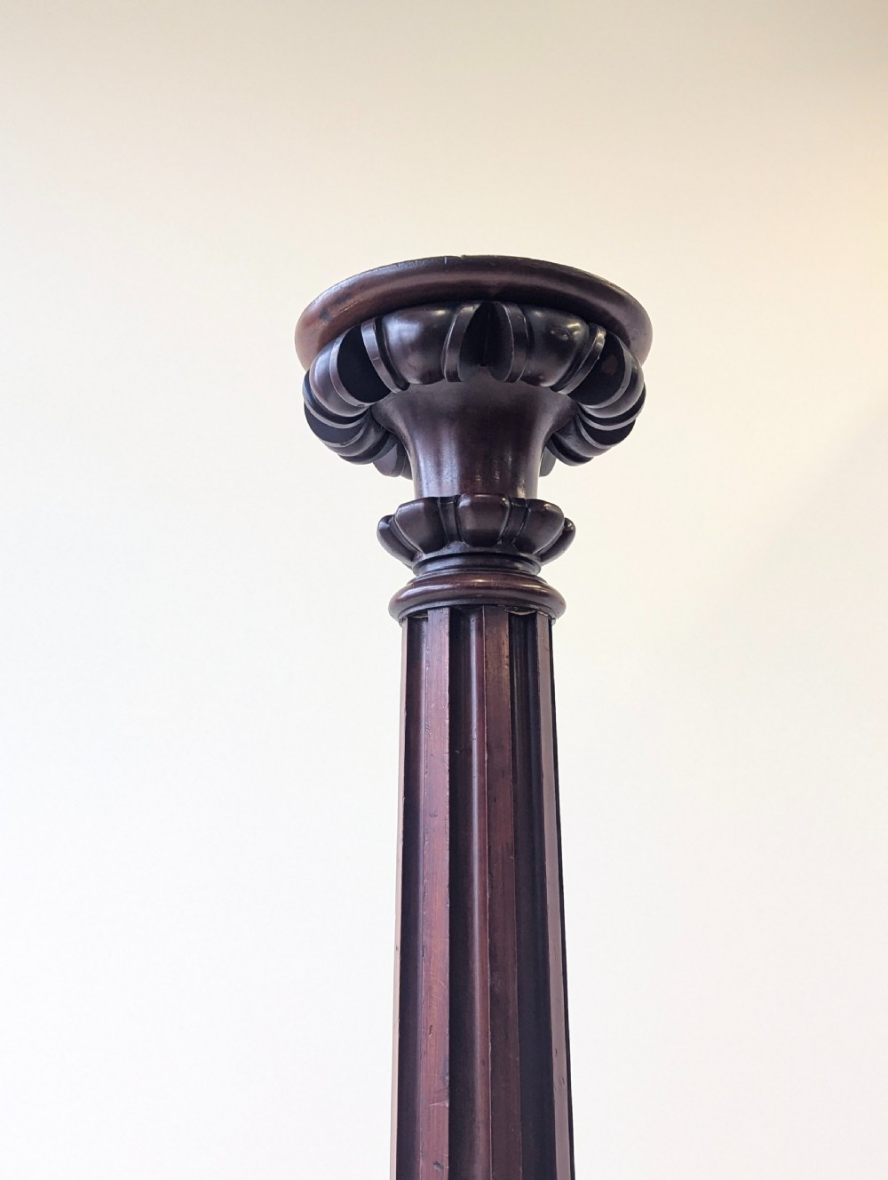 A tall Victorian dark mahogany torchere stand featuring a carved fluted column shaft, gadrooned top rim, and a circular moulded base. View X