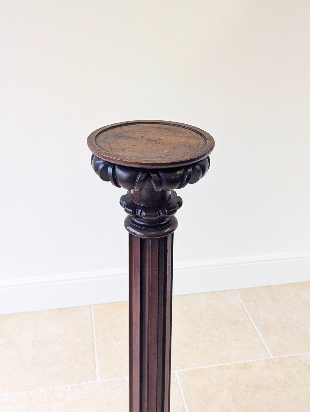 A tall Victorian dark mahogany torchere stand featuring a carved fluted column shaft, gadrooned top rim, and a circular moulded base. View XII