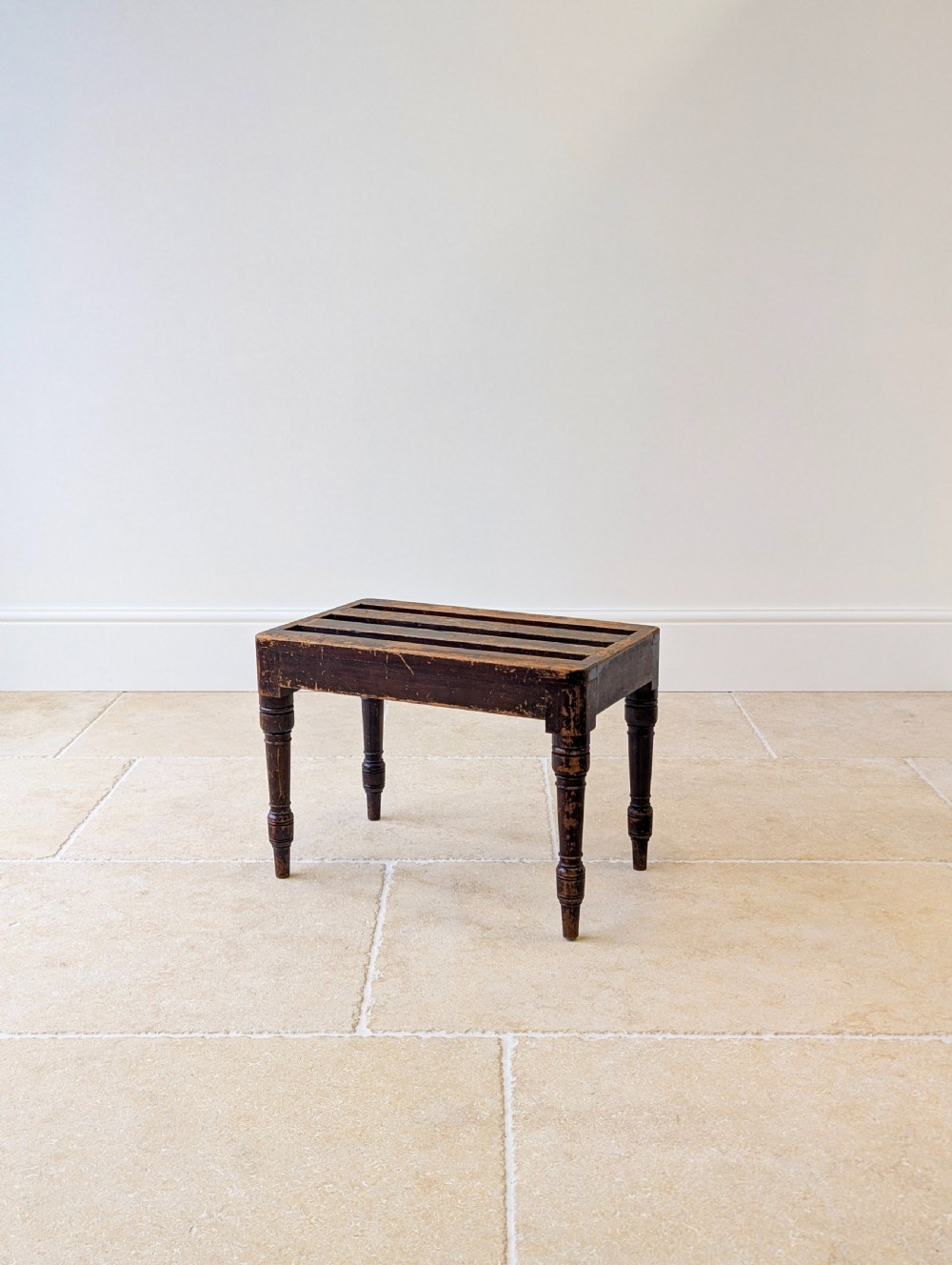 An antique Victorian dark stained beech luggage stand featuring a slatted top and four turned legs. View IV