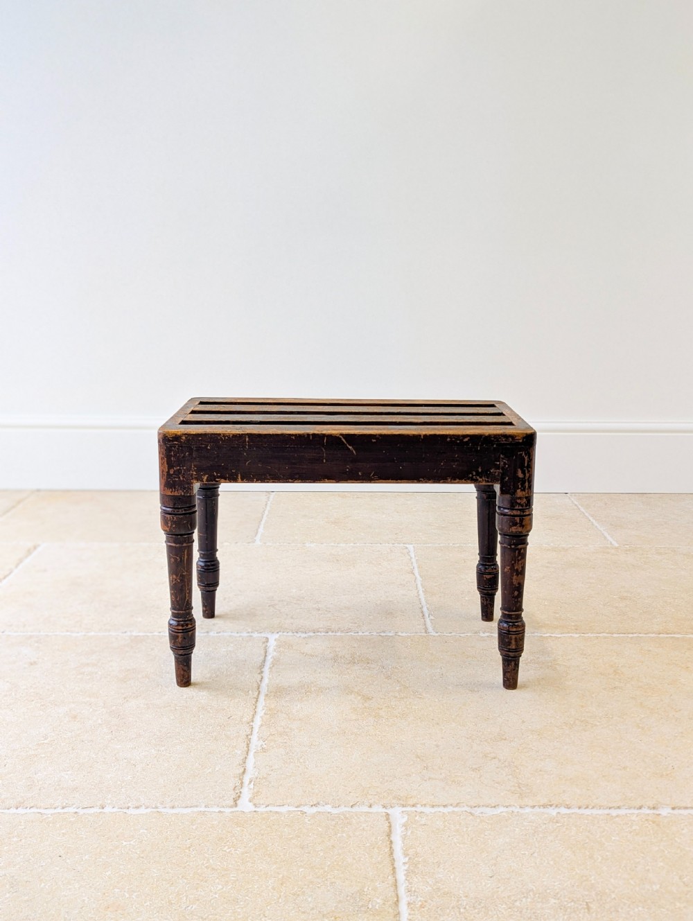 An antique Victorian dark stained beech luggage stand featuring a slatted top and four turned legs. View VI