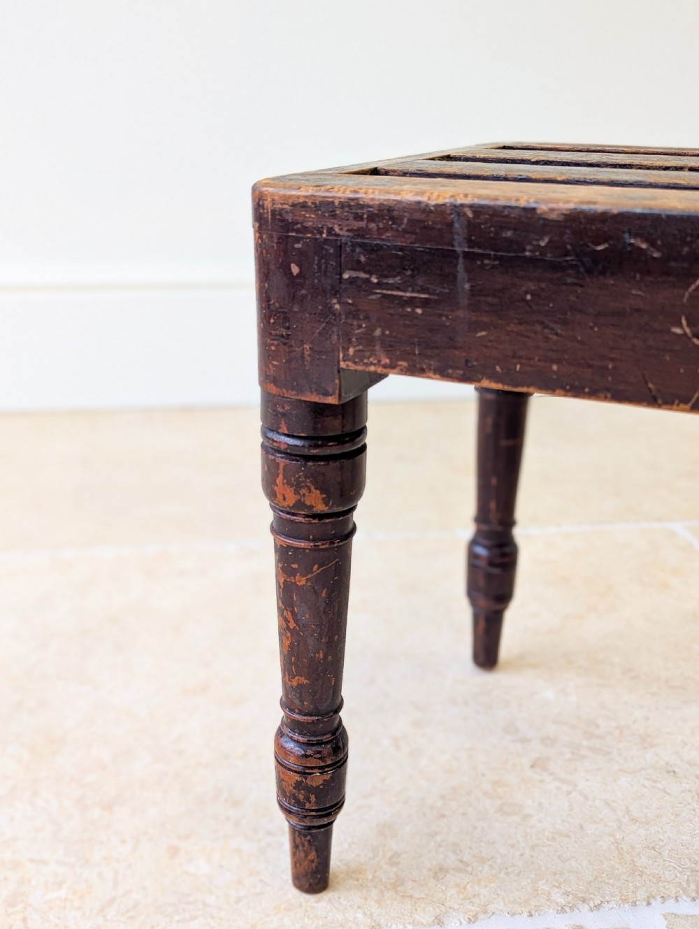 An antique Victorian dark stained beech luggage stand featuring a slatted top and four turned legs. View VII