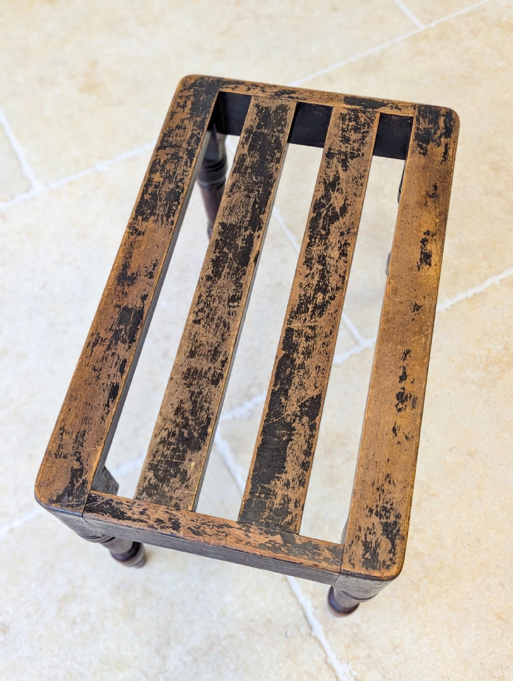 An antique Victorian dark stained beech luggage stand featuring a slatted top and four turned legs. View IX