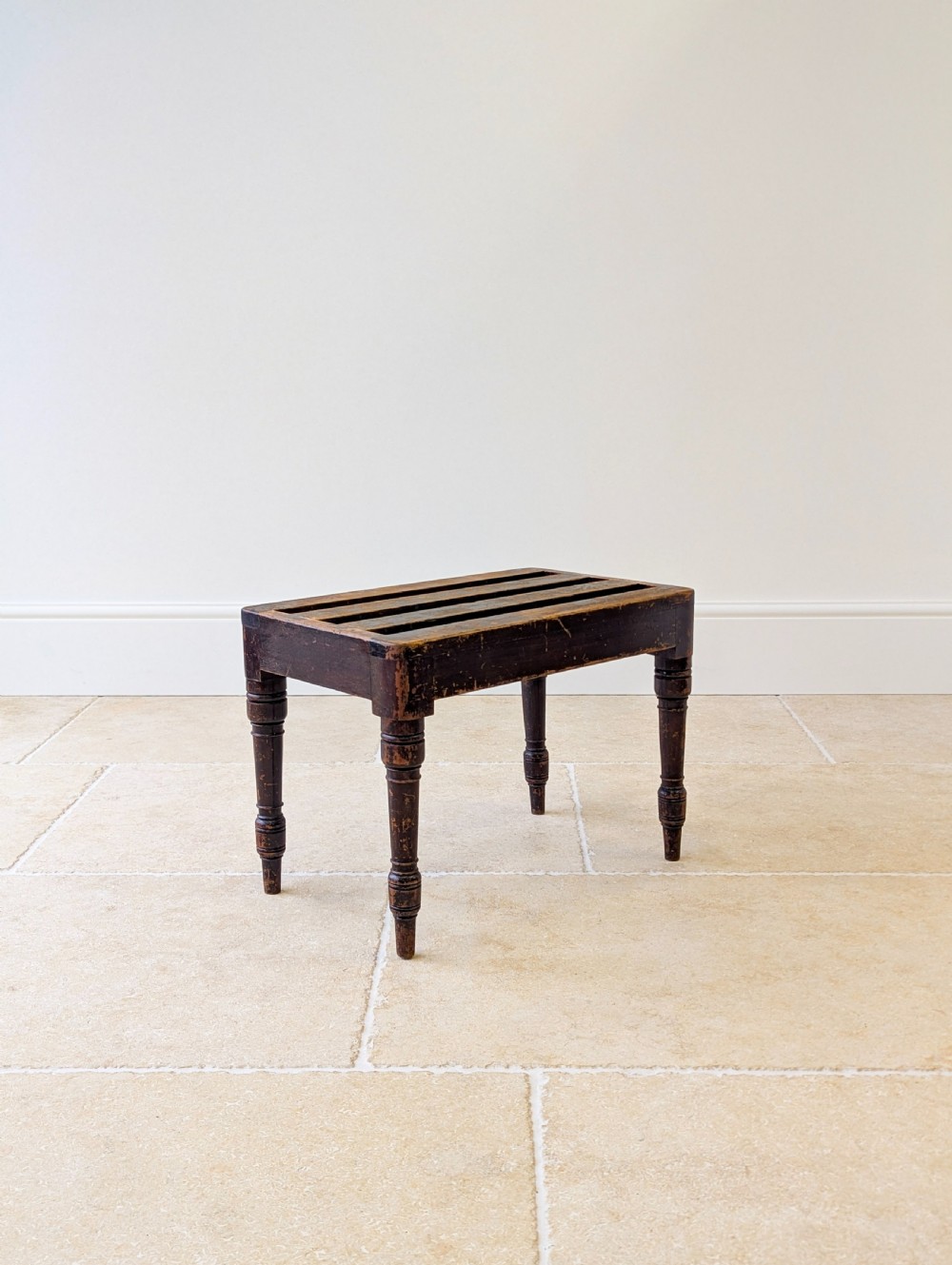 An antique Victorian dark stained beech luggage stand featuring a slatted top and four turned legs. View X
