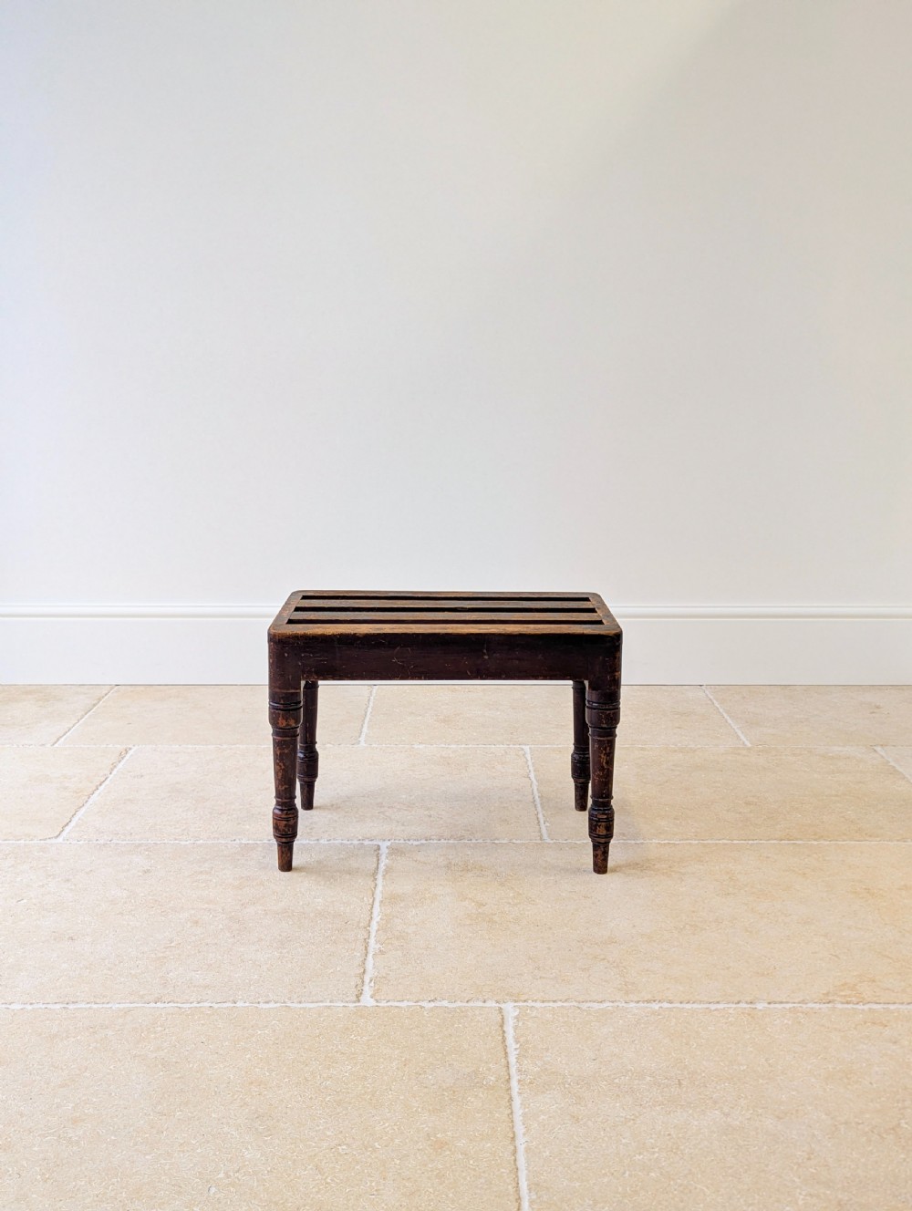 An antique Victorian dark stained beech luggage stand featuring a slatted top and four turned legs. View XII