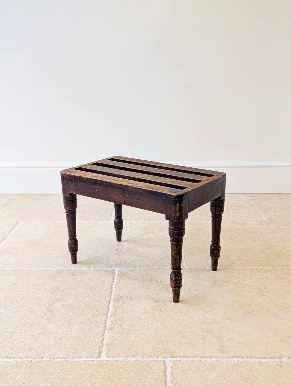 An antique Victorian dark stained beech luggage stand featuring a slatted top and four turned legs. View XVI
