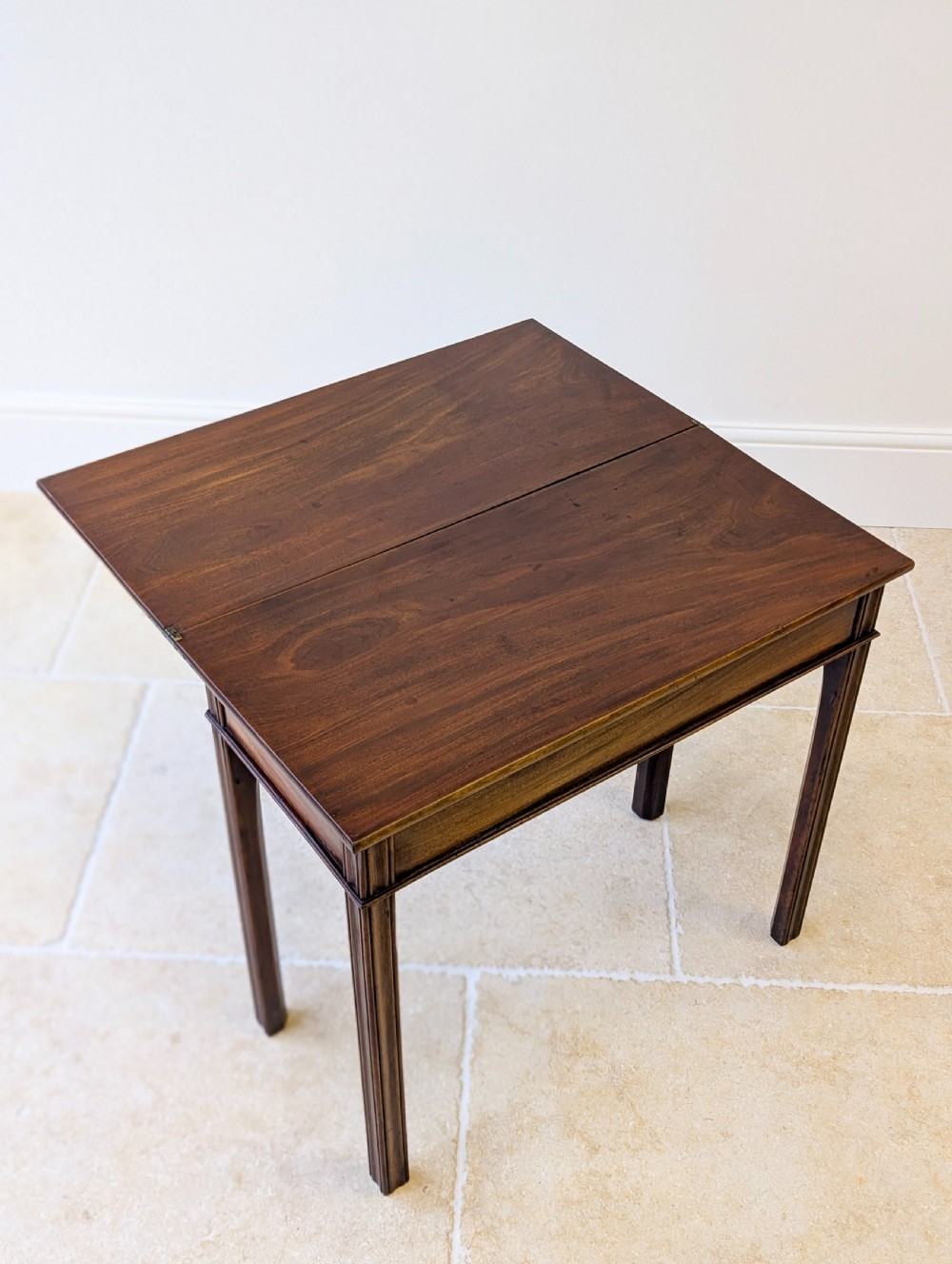 A late 18th-century dark mahogany fold-over tea table featuring reeded straight legs and a polished hinged top. View II