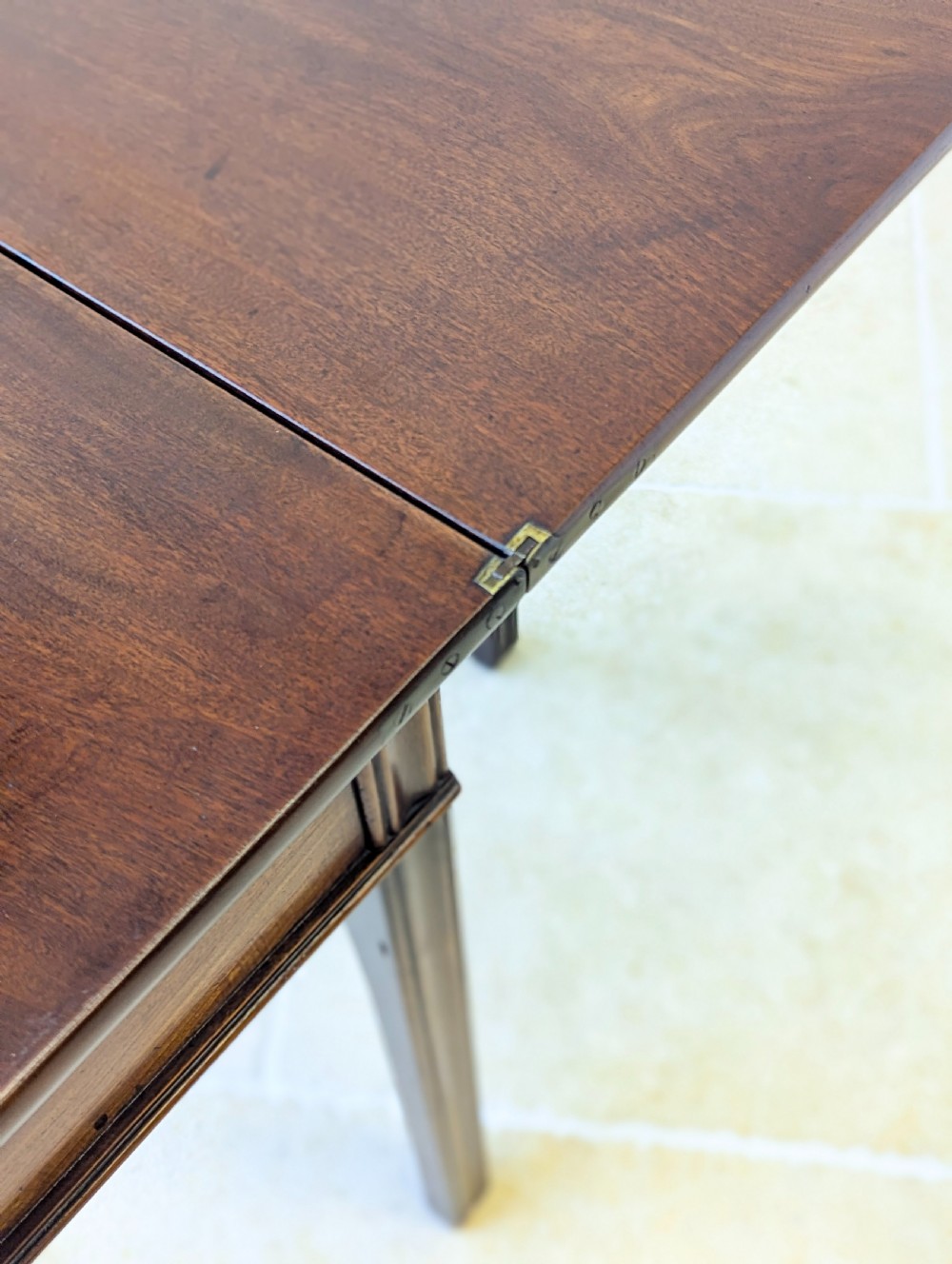 A late 18th-century dark mahogany fold-over tea table featuring reeded straight legs and a polished hinged top. View X