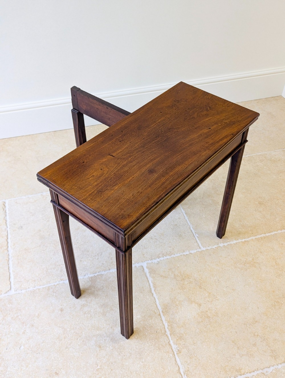 A late 18th-century dark mahogany fold-over tea table featuring reeded straight legs and a polished hinged top. View XIV