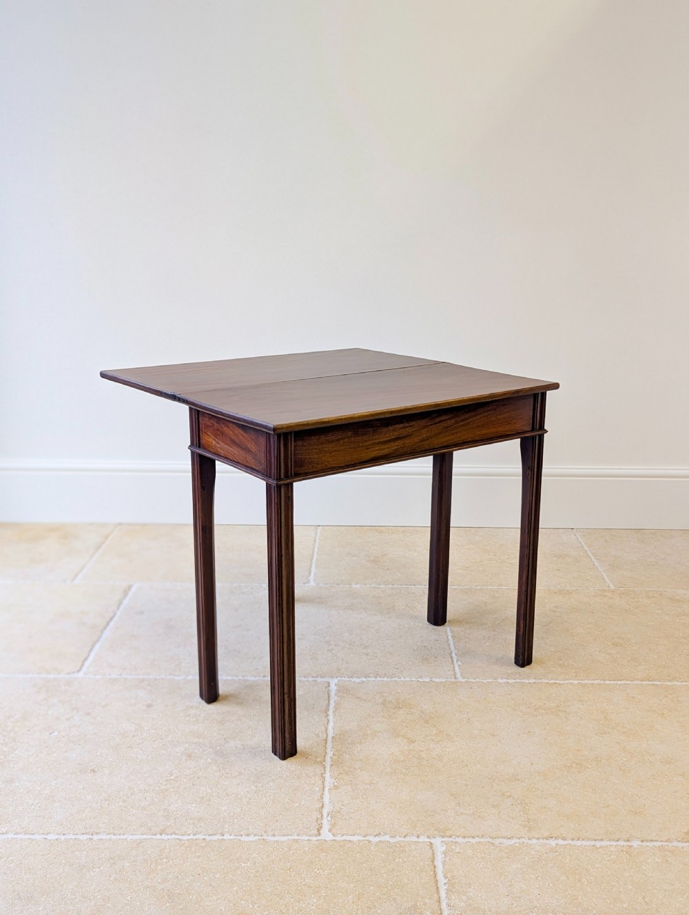 A late 18th-century dark mahogany fold-over tea table featuring reeded straight legs and a polished hinged top. View XV