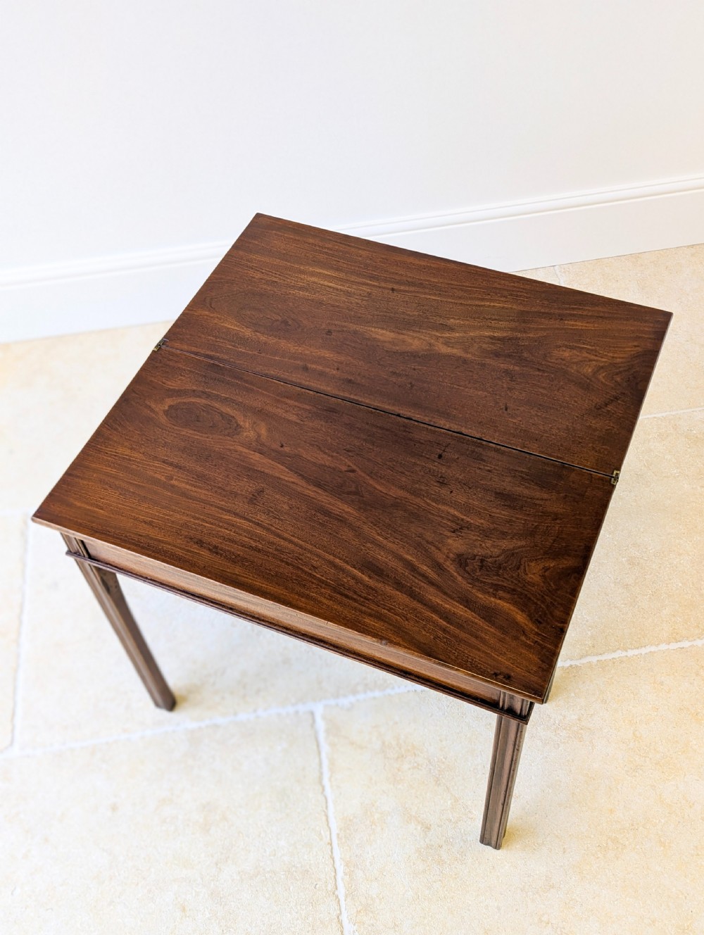 A late 18th-century dark mahogany fold-over tea table featuring reeded straight legs and a polished hinged top. View XVI