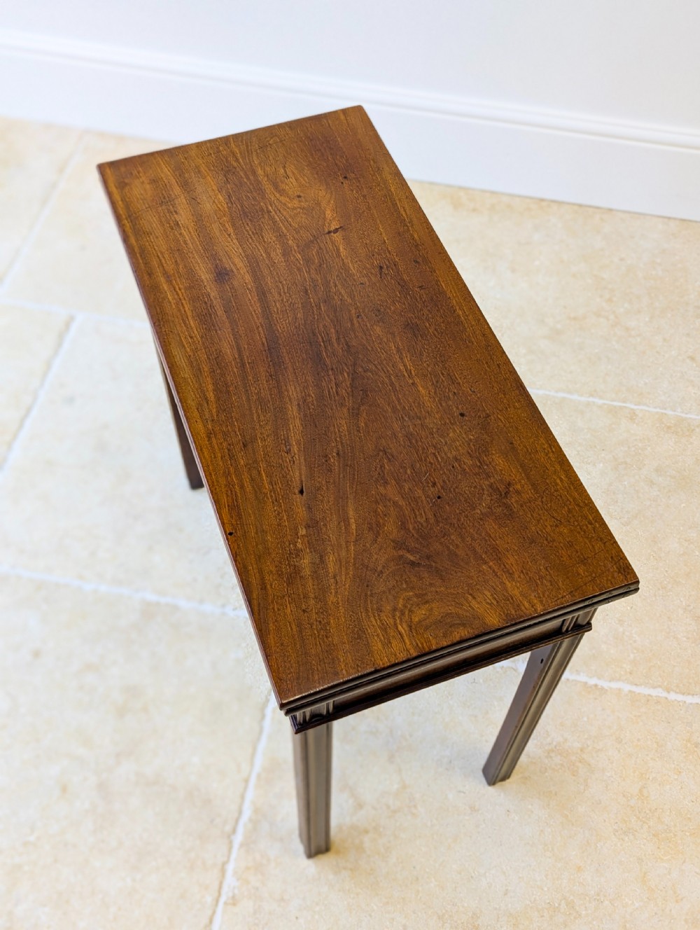A late 18th-century dark mahogany fold-over tea table featuring reeded straight legs and a polished hinged top. View XVII