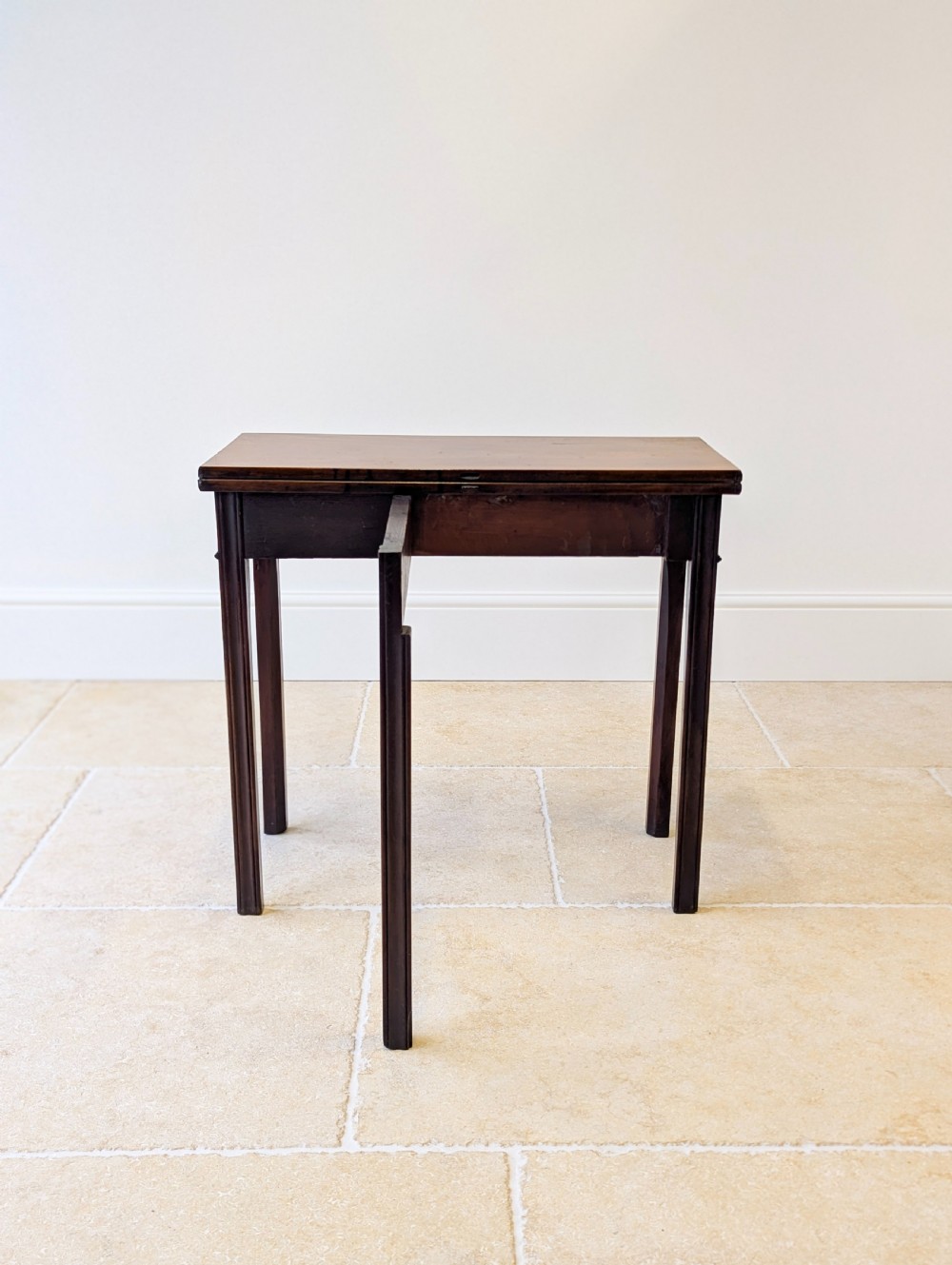 A late 18th-century dark mahogany fold-over tea table featuring reeded straight legs and a polished hinged top. View XIX