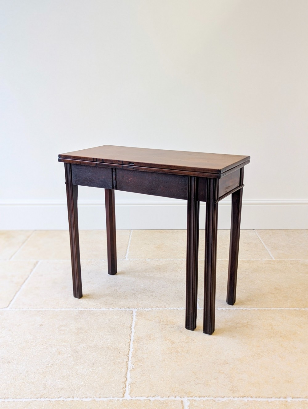 A late 18th-century dark mahogany fold-over tea table featuring reeded straight legs and a polished hinged top. View XX