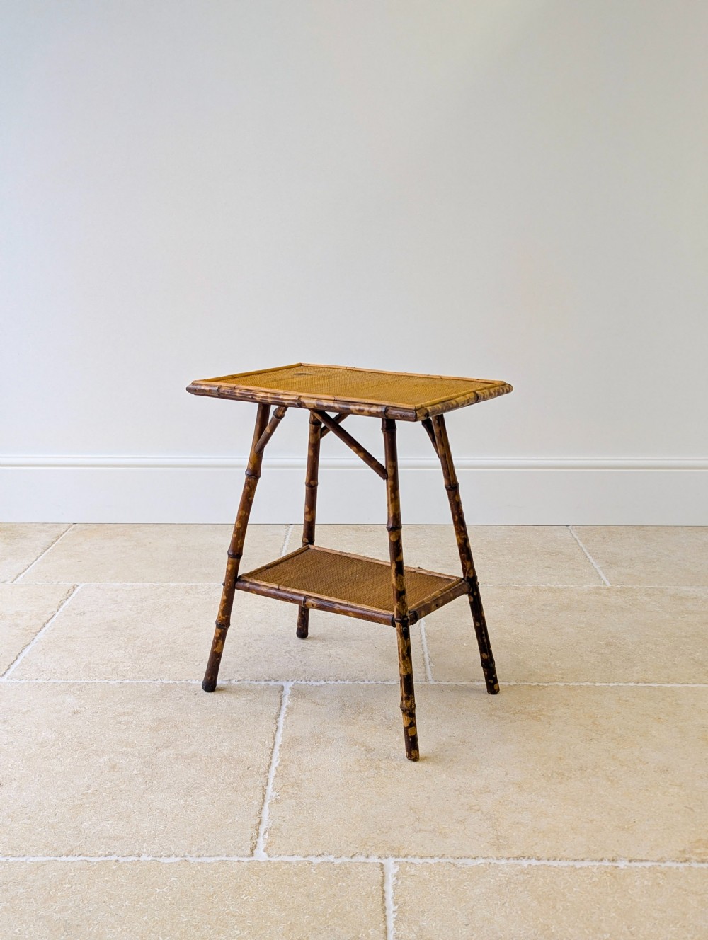 A late Victorian bamboo occasional table featuring a woven cane top surface, lower cane shelf, and splayed mottled bamboo legs.