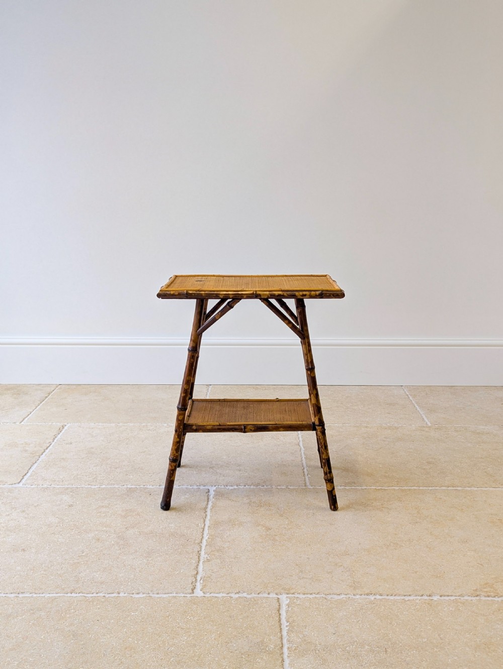 A late Victorian bamboo occasional table featuring a woven cane top surface, lower cane shelf, and splayed mottled bamboo legs. View II