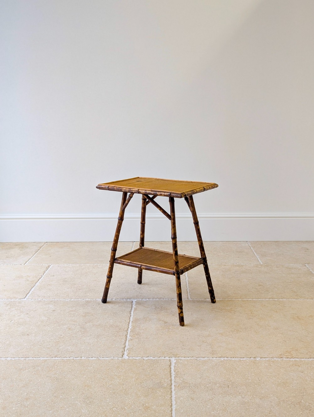 A late Victorian bamboo occasional table featuring a woven cane top surface, lower cane shelf, and splayed mottled bamboo legs. View IV