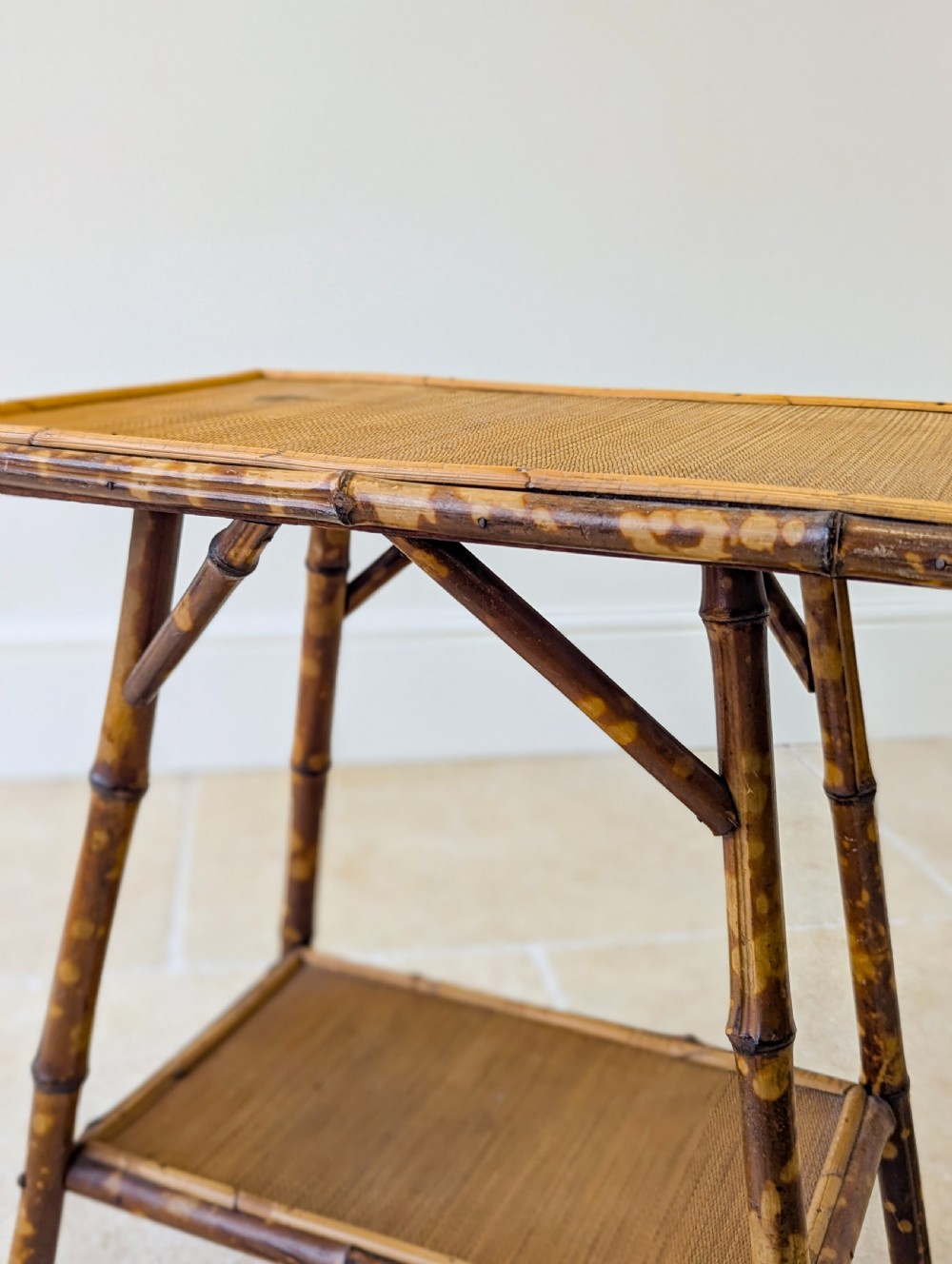 A late Victorian bamboo occasional table featuring a woven cane top surface, lower cane shelf, and splayed mottled bamboo legs. View V