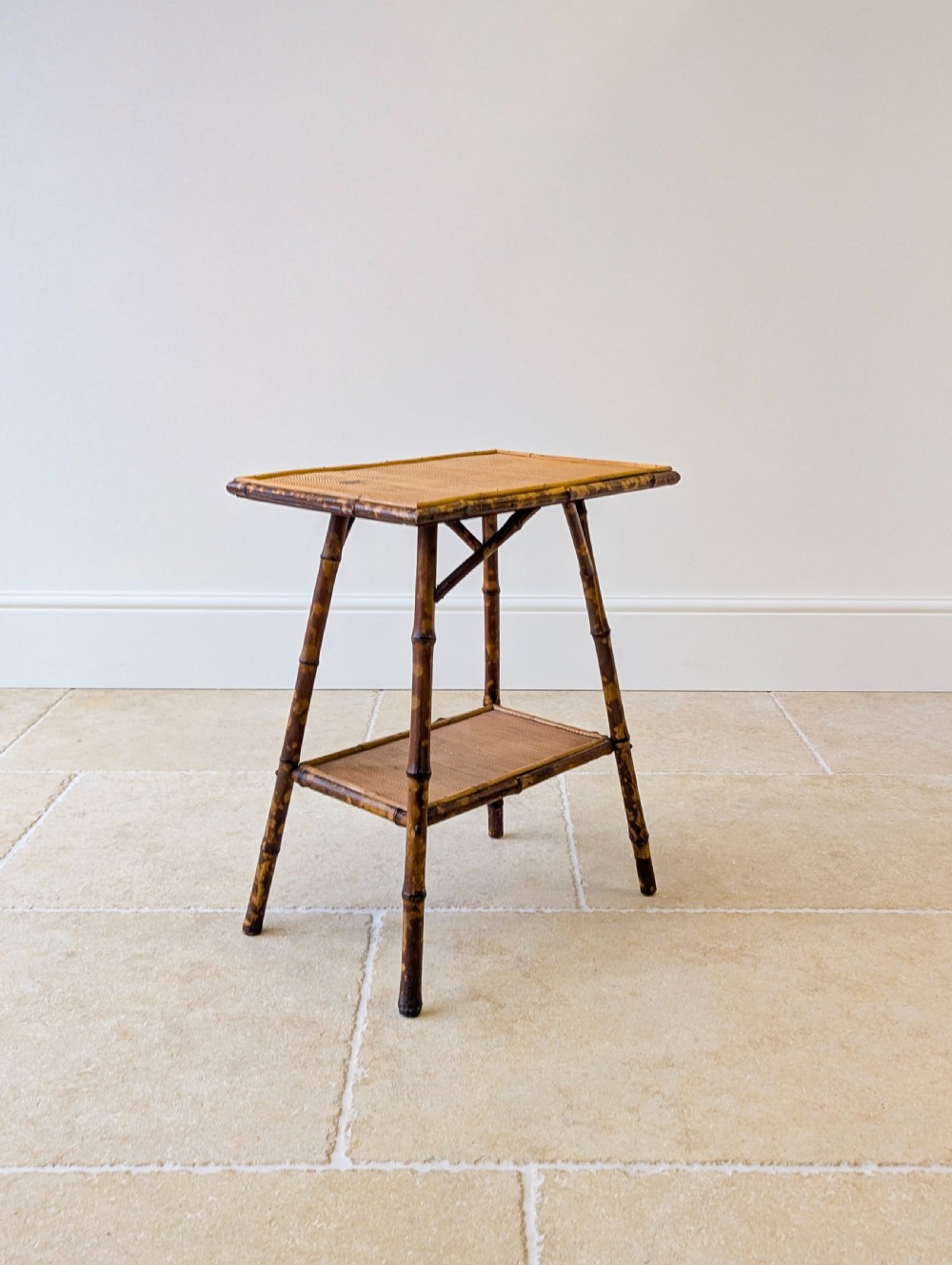 A late Victorian bamboo occasional table featuring a woven cane top surface, lower cane shelf, and splayed mottled bamboo legs. View VI