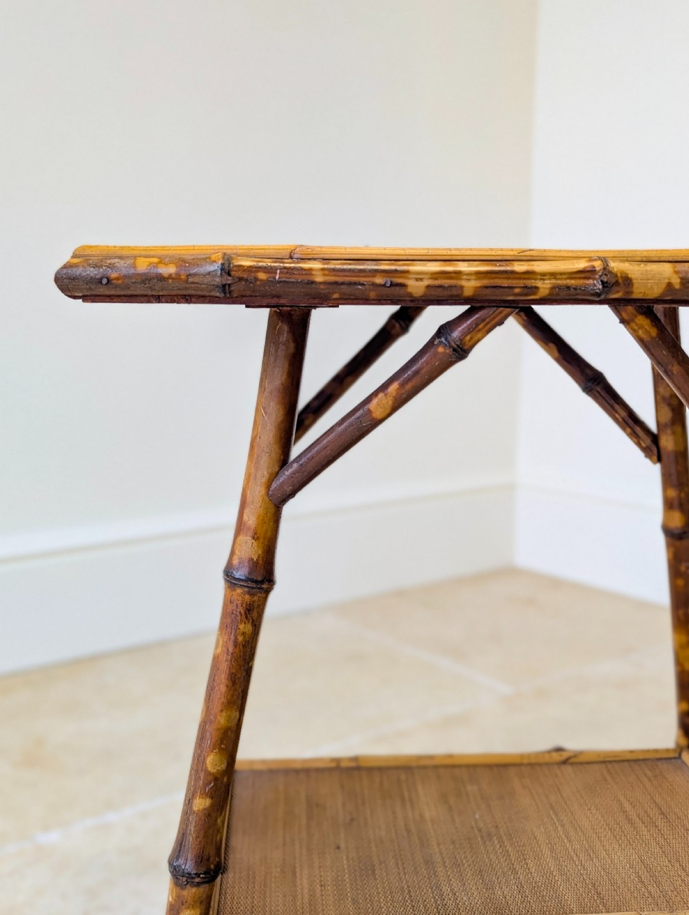 A late Victorian bamboo occasional table featuring a woven cane top surface, lower cane shelf, and splayed mottled bamboo legs. View IX