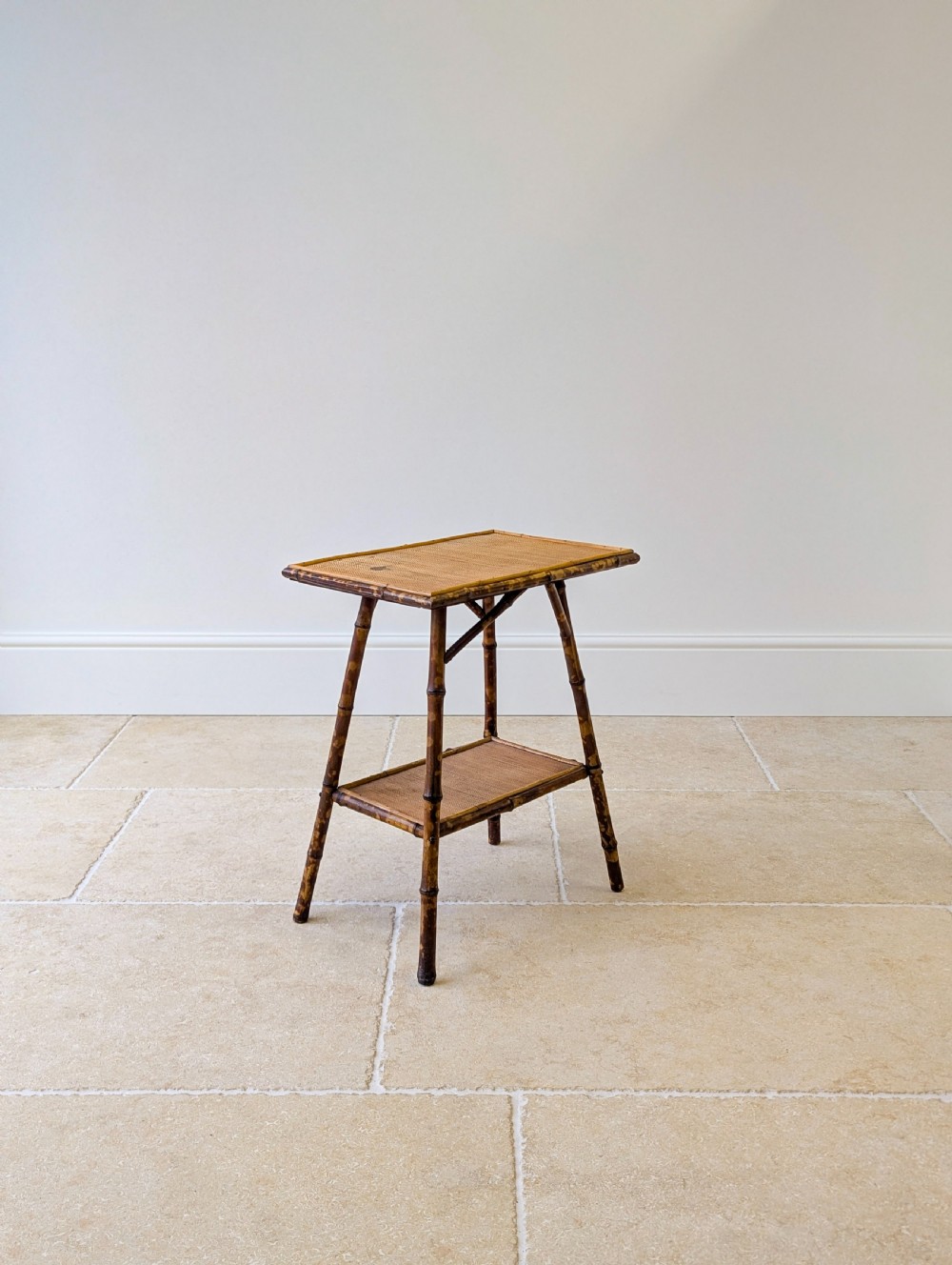 A late Victorian bamboo occasional table featuring a woven cane top surface, lower cane shelf, and splayed mottled bamboo legs. View X