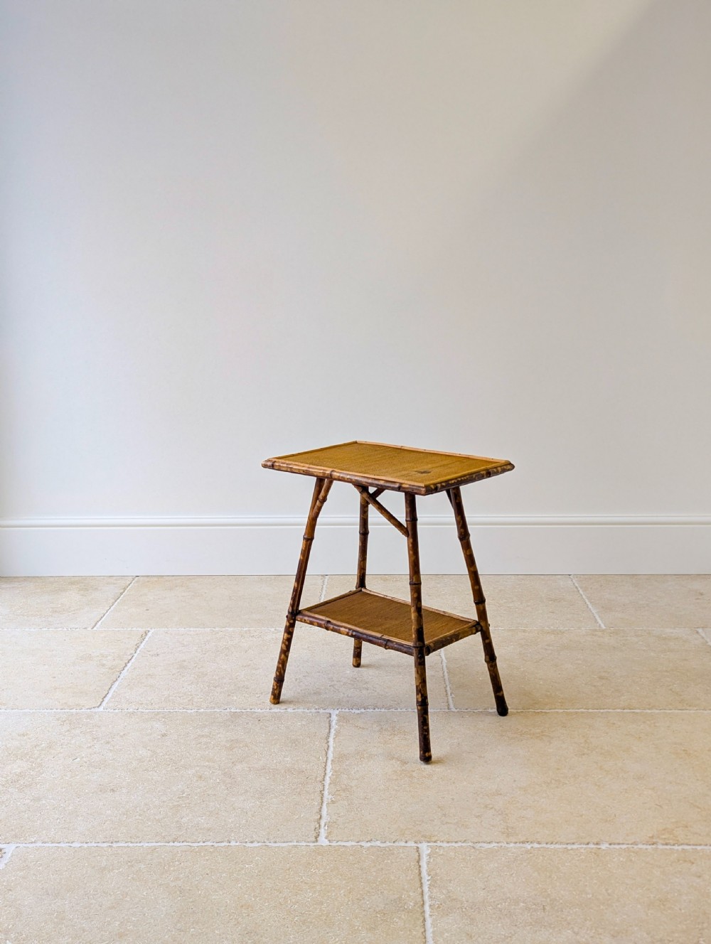A late Victorian bamboo occasional table featuring a woven cane top surface, lower cane shelf, and splayed mottled bamboo legs. View XV