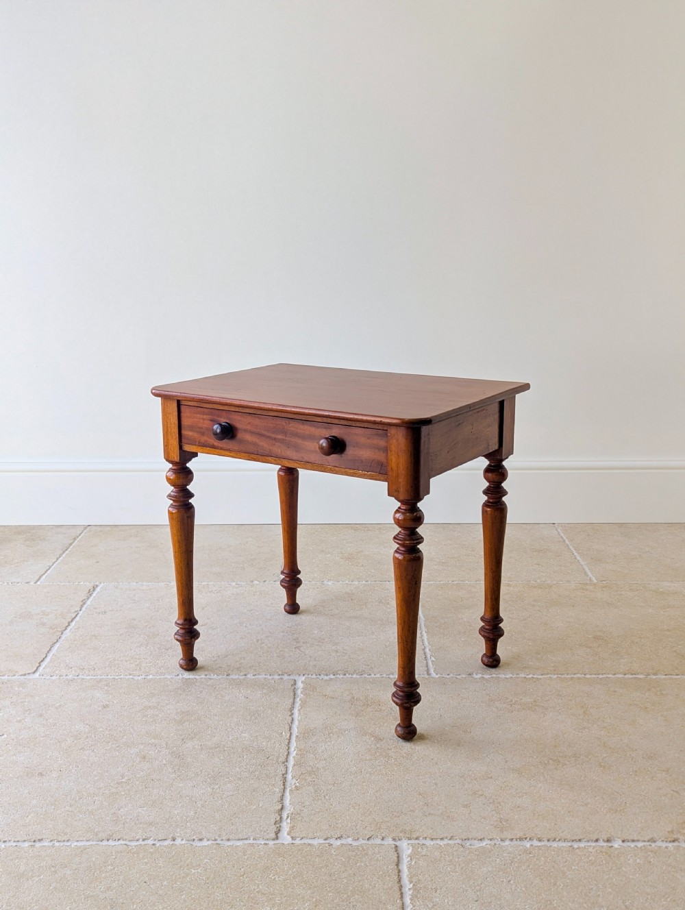 A late Victorian mahogany side table featuring a rectangular top, single drawer with two turned wooden knobs, and four turned legs.