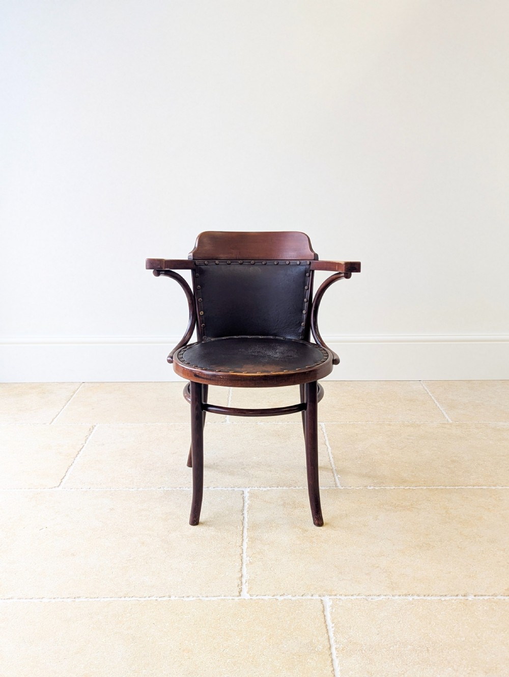 An antique Edwardian bentwood armchair featuring dark brown steam-bent beech wood, sweeping armrests, and a black leather studded seat and backrest. View III