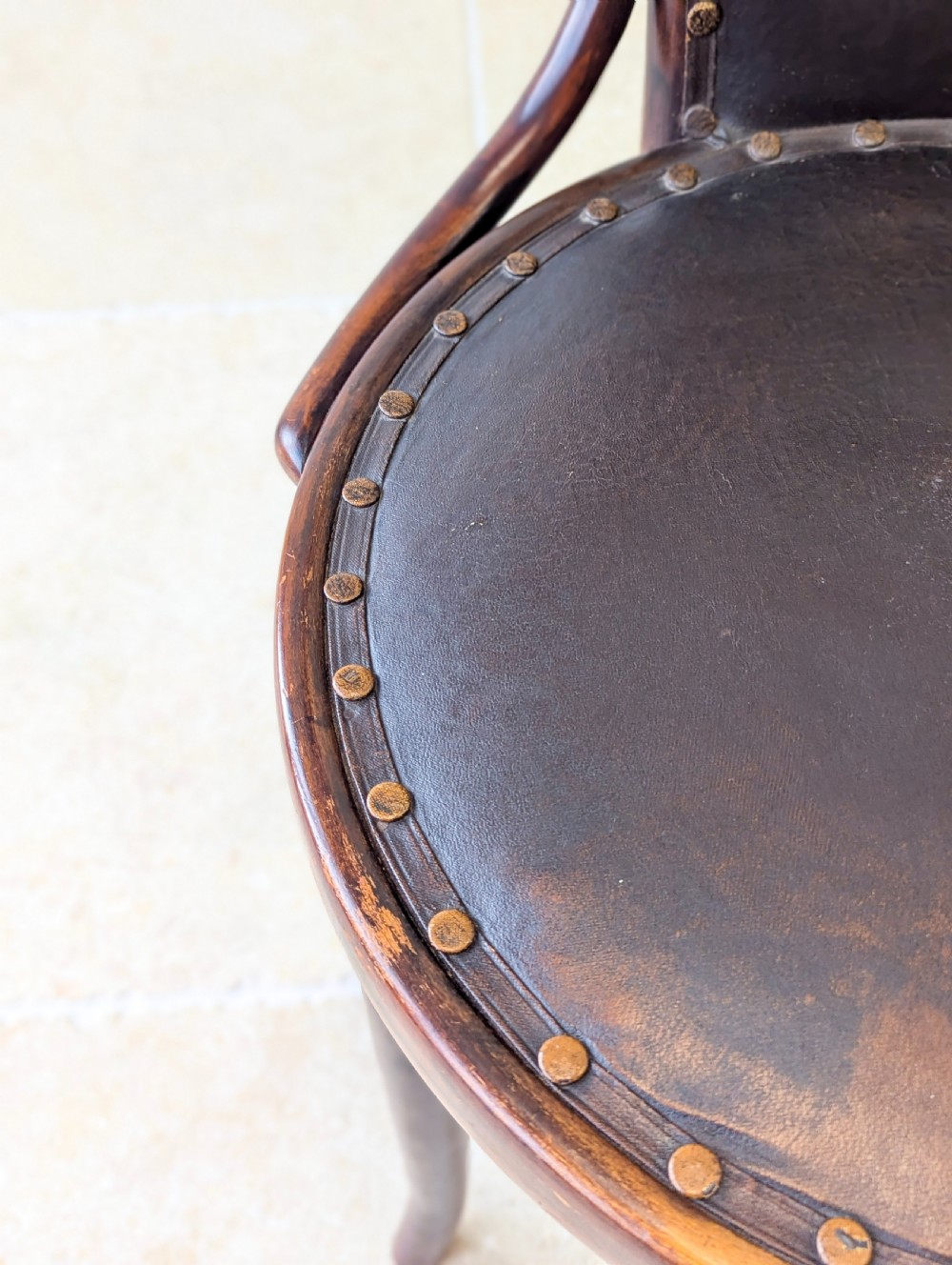 An antique Edwardian bentwood armchair featuring dark brown steam-bent beech wood, sweeping armrests, and a black leather studded seat and backrest. View VI