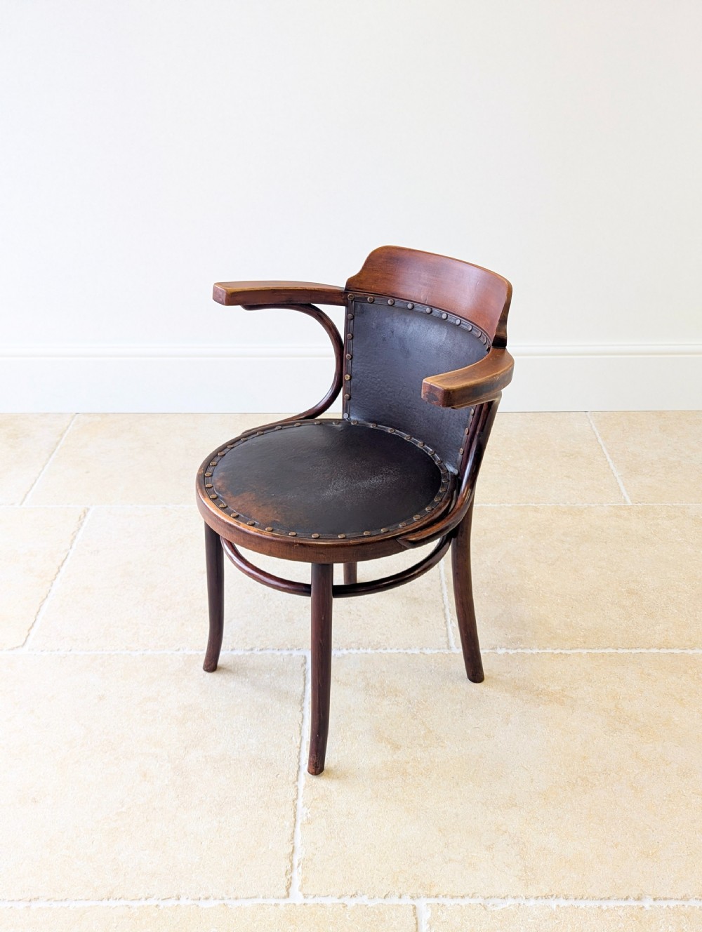 An antique Edwardian bentwood armchair featuring dark brown steam-bent beech wood, sweeping armrests, and a black leather studded seat and backrest. View VII