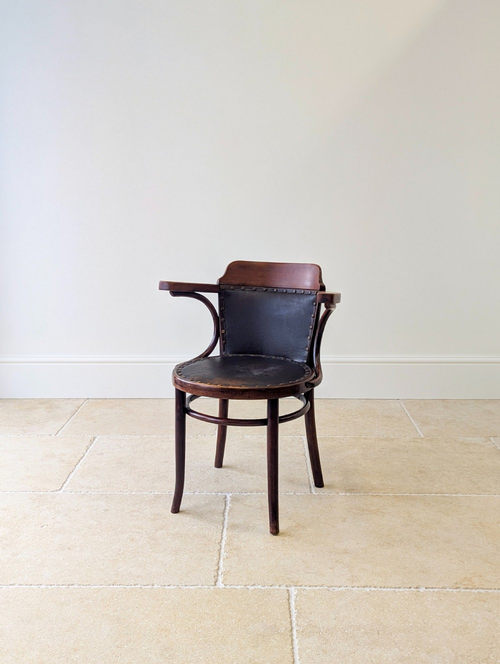 An antique Edwardian bentwood armchair featuring dark brown steam-bent beech wood, sweeping armrests, and a black leather studded seat and backrest. View VIII