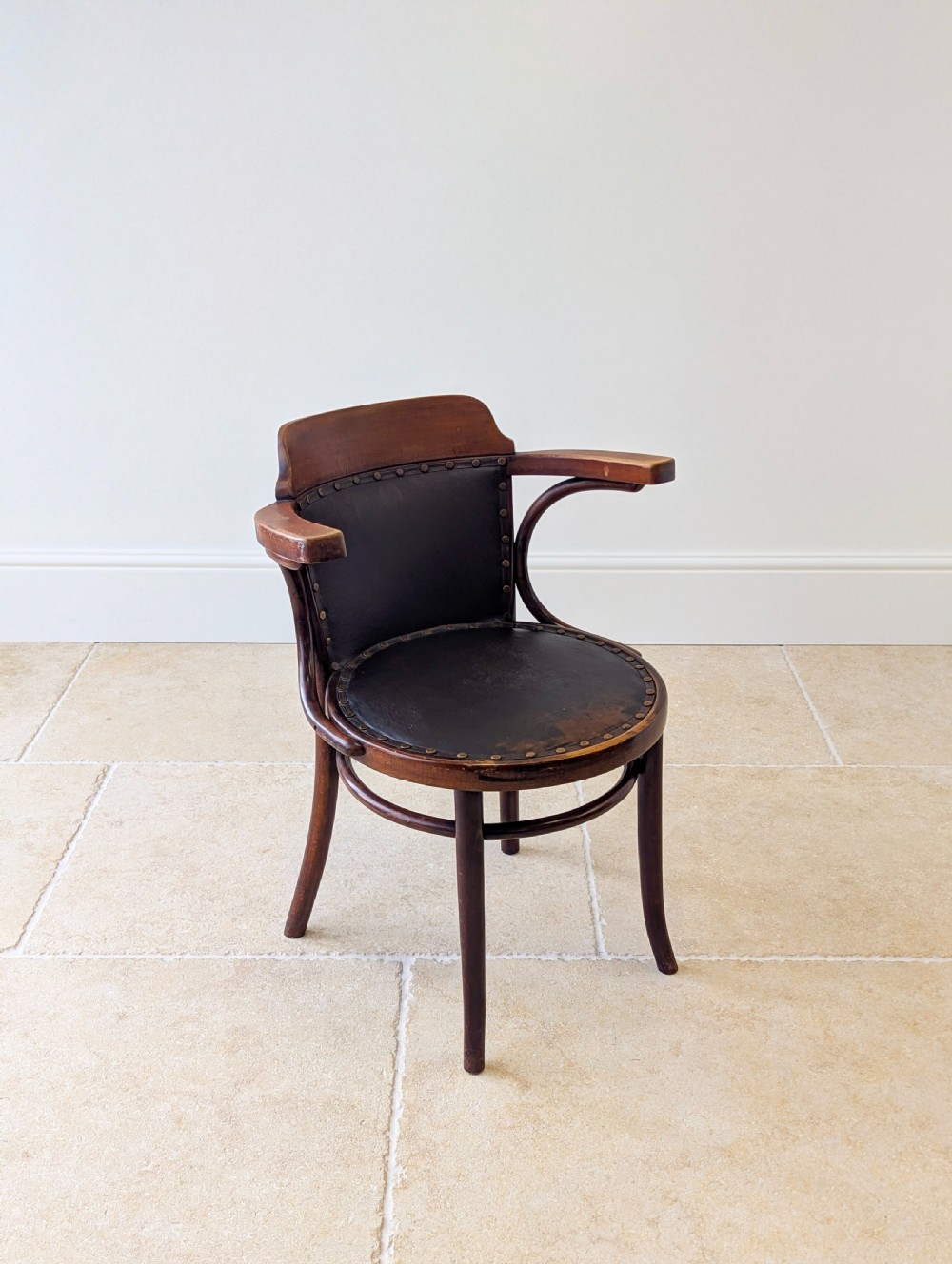 An antique Edwardian bentwood armchair featuring dark brown steam-bent beech wood, sweeping armrests, and a black leather studded seat and backrest. View XI