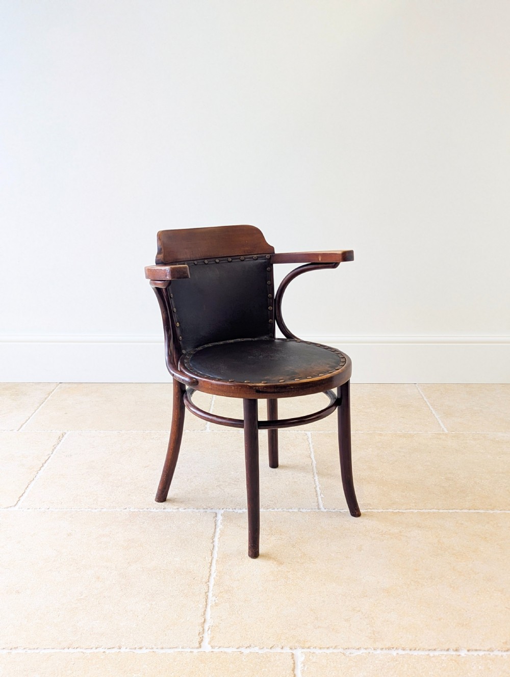 An antique Edwardian bentwood armchair featuring dark brown steam-bent beech wood, sweeping armrests, and a black leather studded seat and backrest. View XIII
