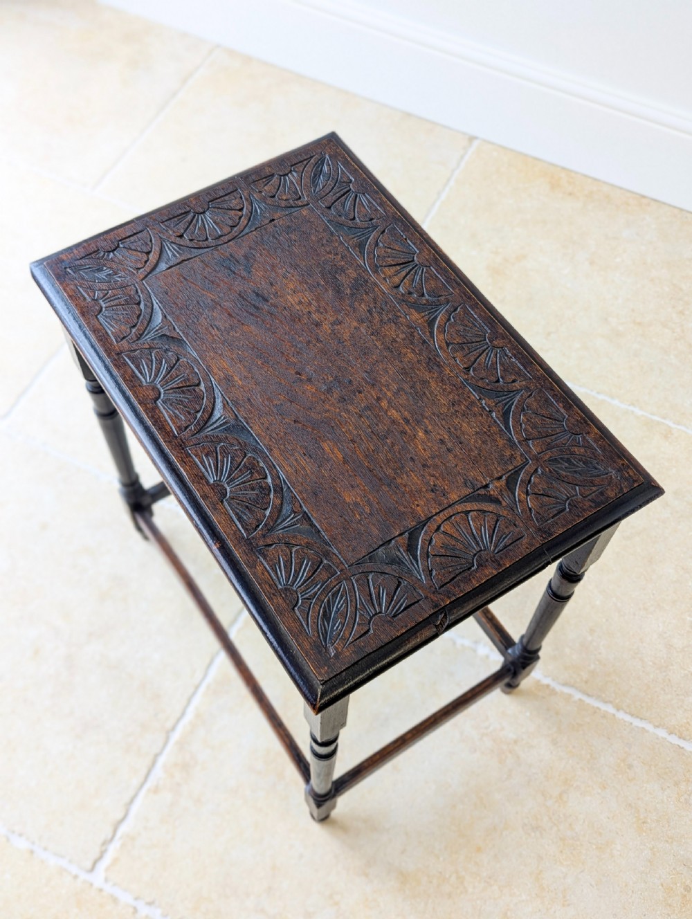 An Edwardian dark oak rectangular occasional table featuring a relief-carved foliate border on the top, slender turned legs, and lower perimeter stretchers. View II