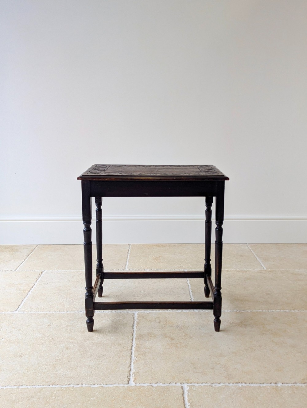 An Edwardian dark oak rectangular occasional table featuring a relief-carved foliate border on the top, slender turned legs, and lower perimeter stretchers. View III