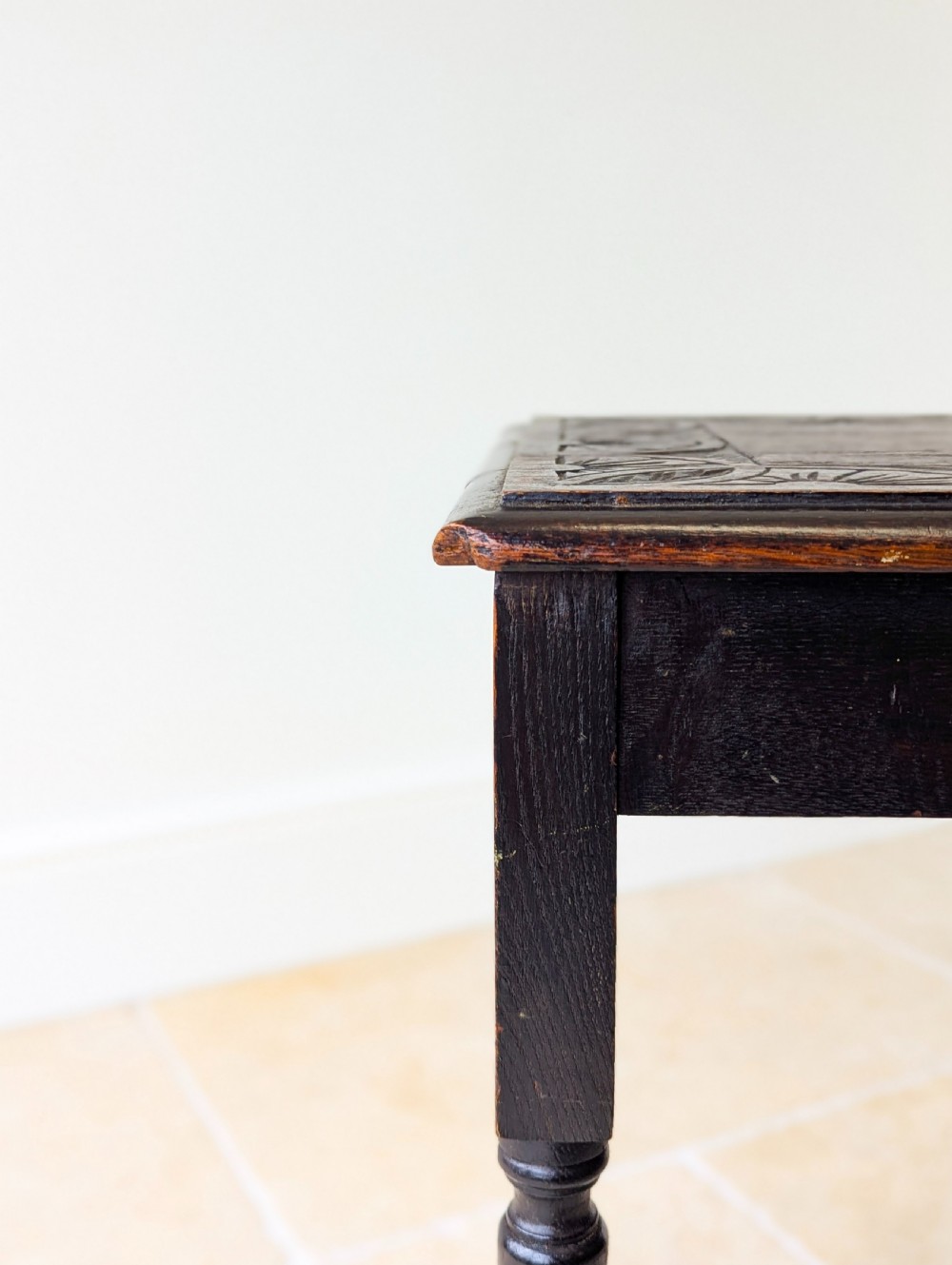 An Edwardian dark oak rectangular occasional table featuring a relief-carved foliate border on the top, slender turned legs, and lower perimeter stretchers. View IV