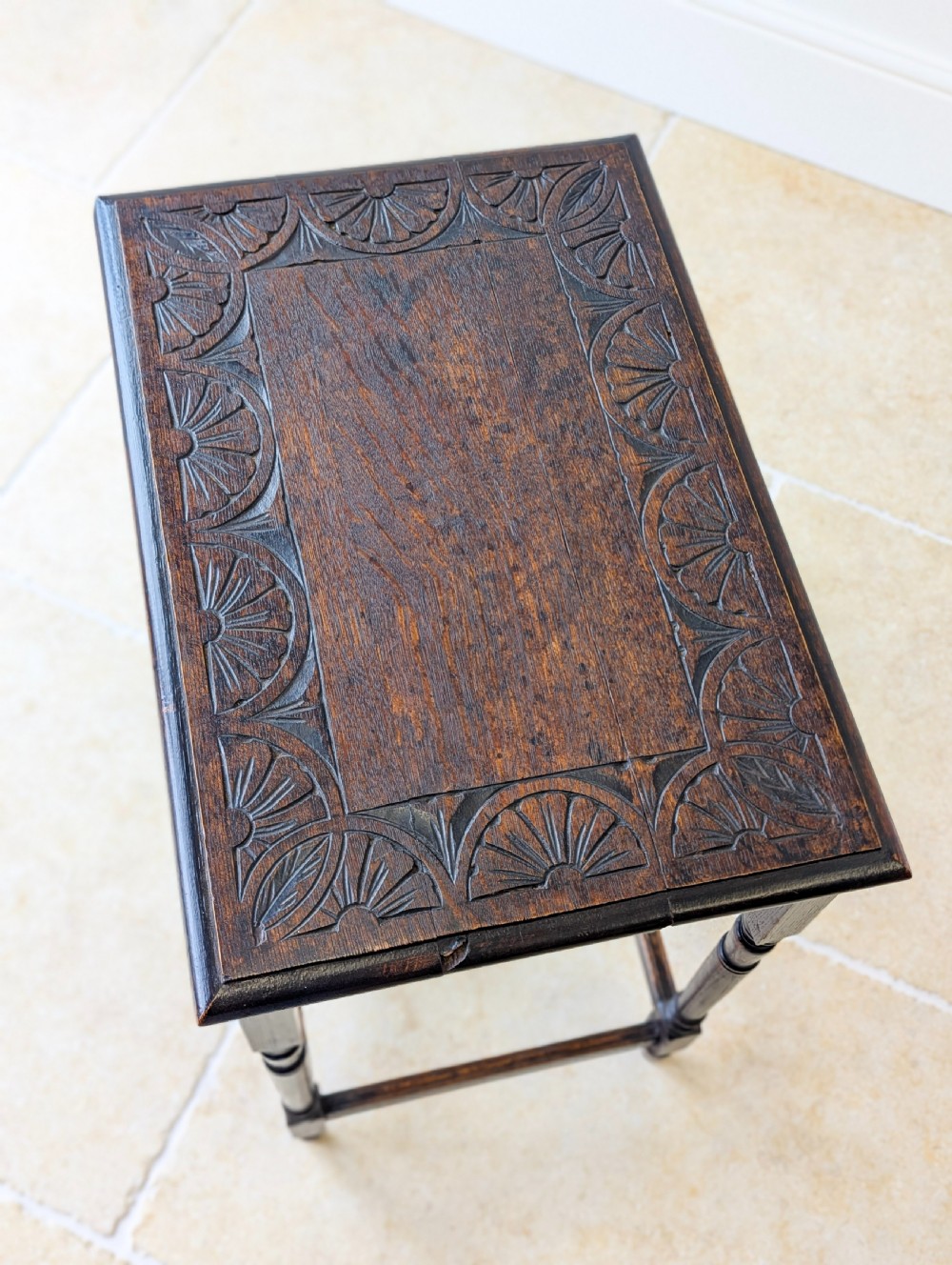An Edwardian dark oak rectangular occasional table featuring a relief-carved foliate border on the top, slender turned legs, and lower perimeter stretchers. View VI