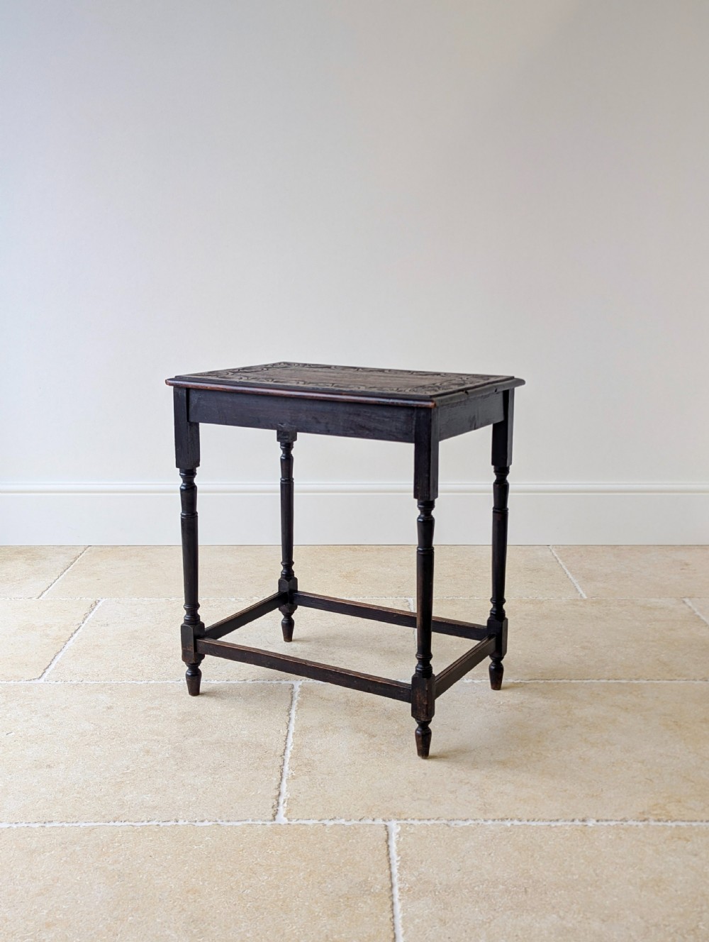 An Edwardian dark oak rectangular occasional table featuring a relief-carved foliate border on the top, slender turned legs, and lower perimeter stretchers. View VII