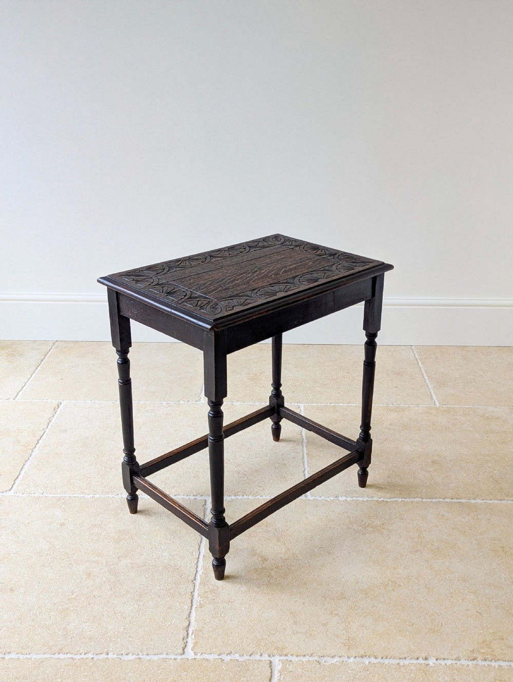 An Edwardian dark oak rectangular occasional table featuring a relief-carved foliate border on the top, slender turned legs, and lower perimeter stretchers. View IX