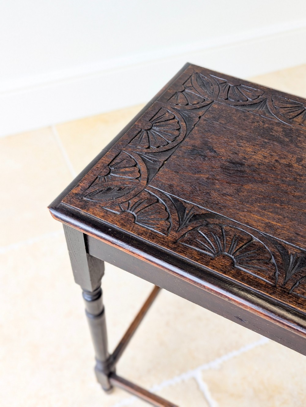 An Edwardian dark oak rectangular occasional table featuring a relief-carved foliate border on the top, slender turned legs, and lower perimeter stretchers. View X