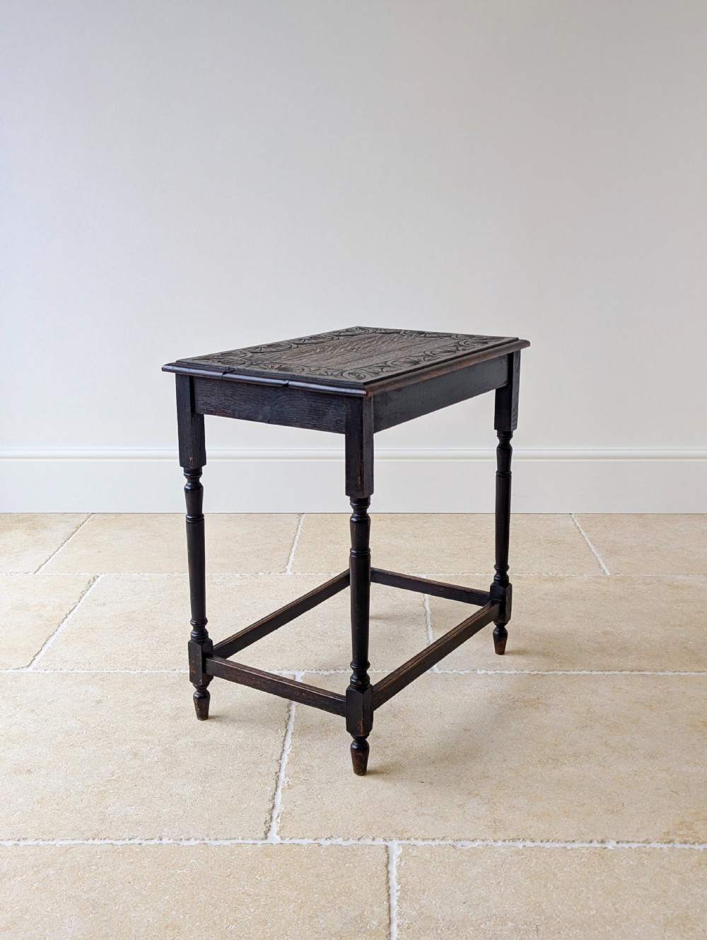 An Edwardian dark oak rectangular occasional table featuring a relief-carved foliate border on the top, slender turned legs, and lower perimeter stretchers. View XI