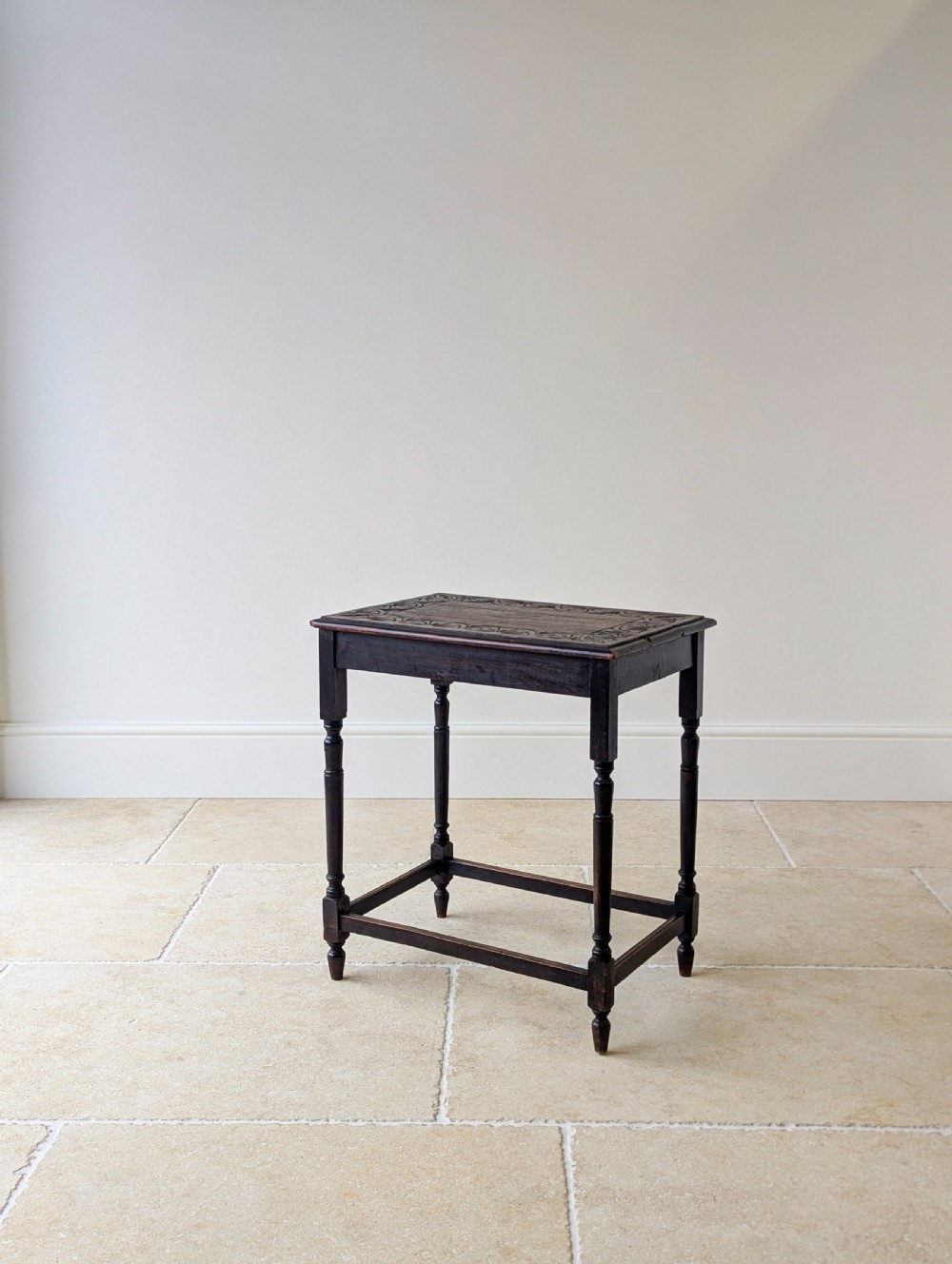 An Edwardian dark oak rectangular occasional table featuring a relief-carved foliate border on the top, slender turned legs, and lower perimeter stretchers. View XII