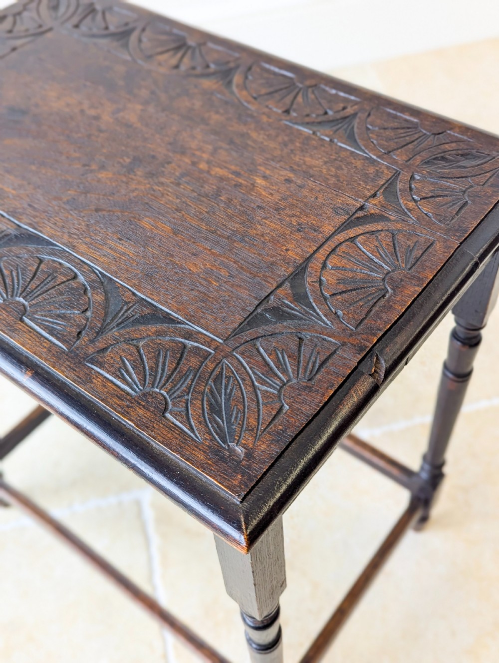 An Edwardian dark oak rectangular occasional table featuring a relief-carved foliate border on the top, slender turned legs, and lower perimeter stretchers. View XIII