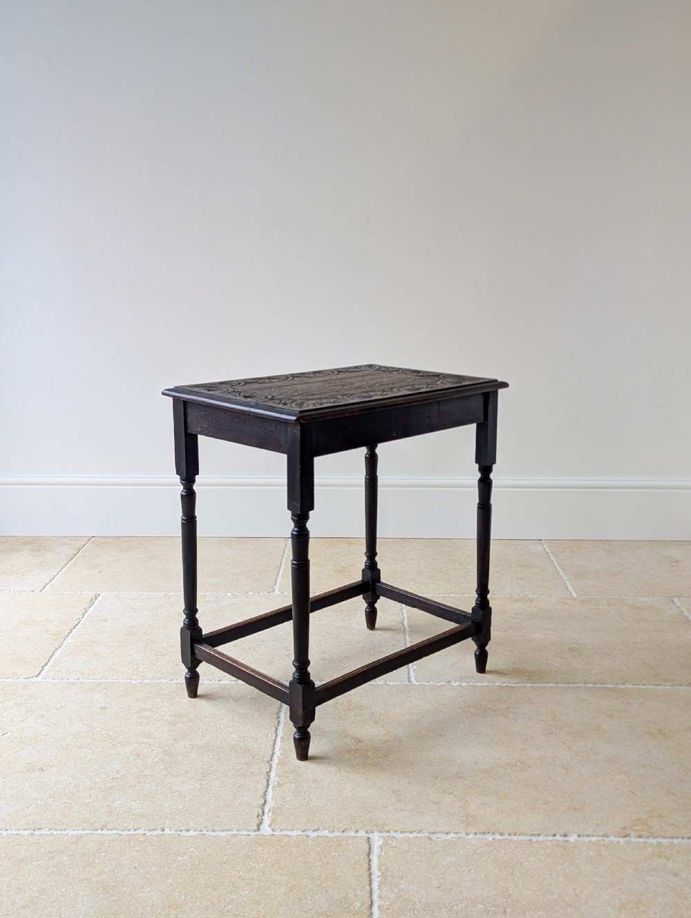An Edwardian dark oak rectangular occasional table featuring a relief-carved foliate border on the top, slender turned legs, and lower perimeter stretchers. View XIV
