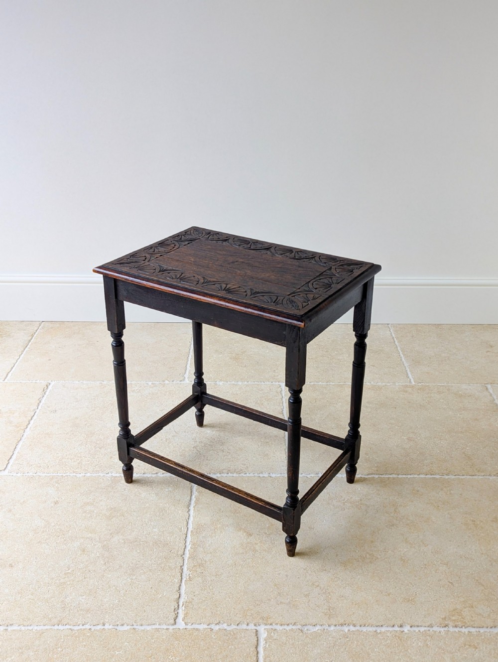 An Edwardian dark oak rectangular occasional table featuring a relief-carved foliate border on the top, slender turned legs, and lower perimeter stretchers. View XVI