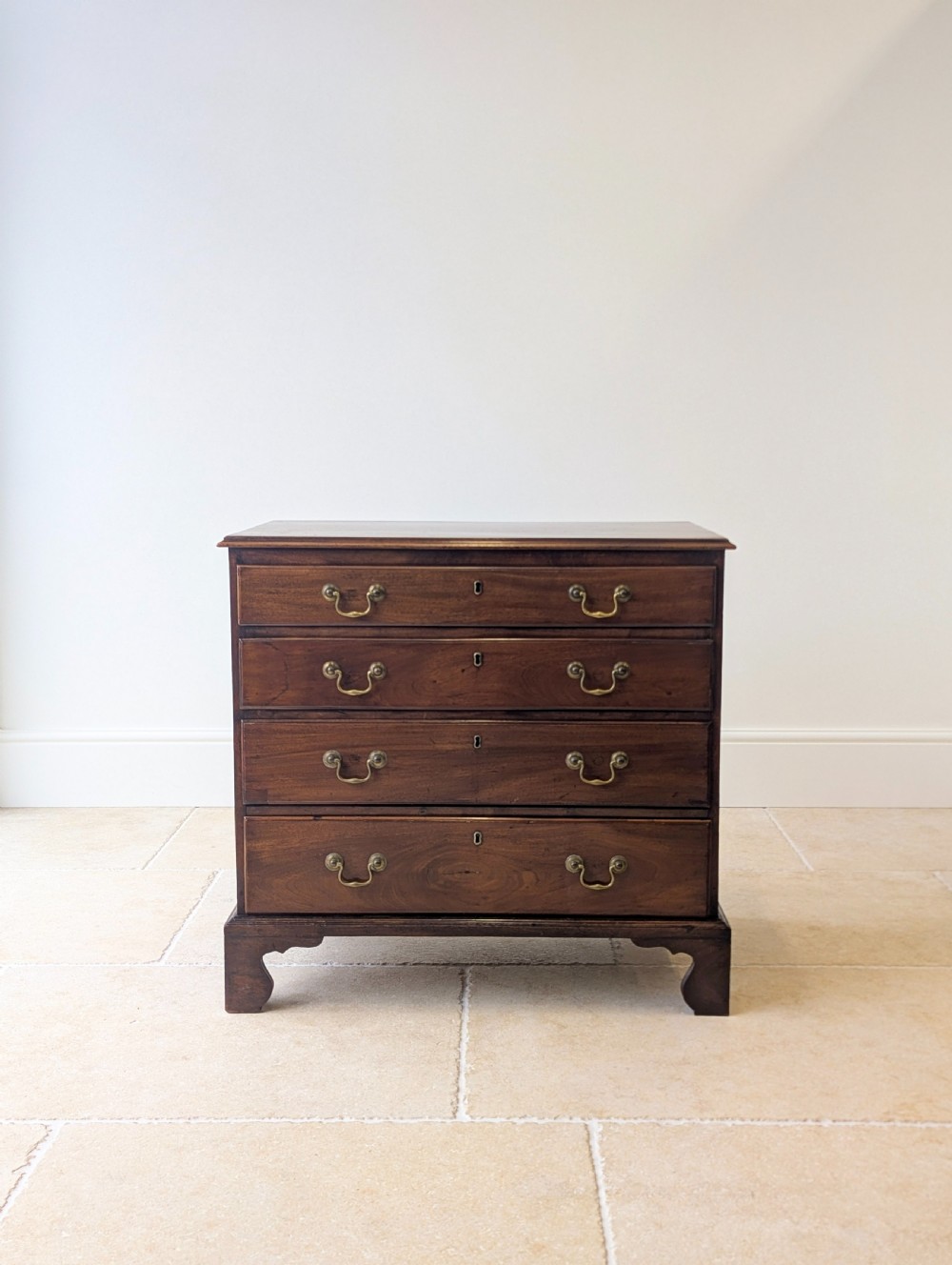 An 18th-century George III mahogany chest of drawers featuring four graduated drawers with brass swan-neck handles and bracket feet. View II