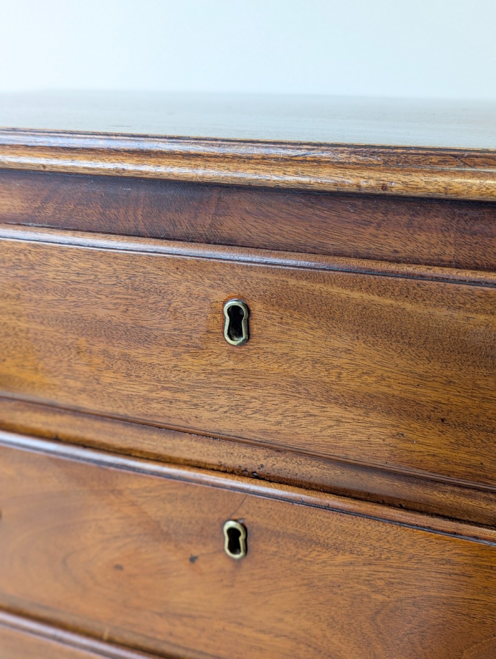 An 18th-century George III mahogany chest of drawers featuring four graduated drawers with brass swan-neck handles and bracket feet. View V