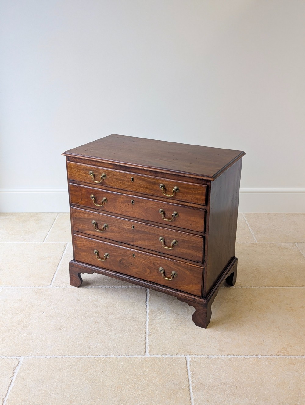 An 18th-century George III mahogany chest of drawers featuring four graduated drawers with brass swan-neck handles and bracket feet. View VI